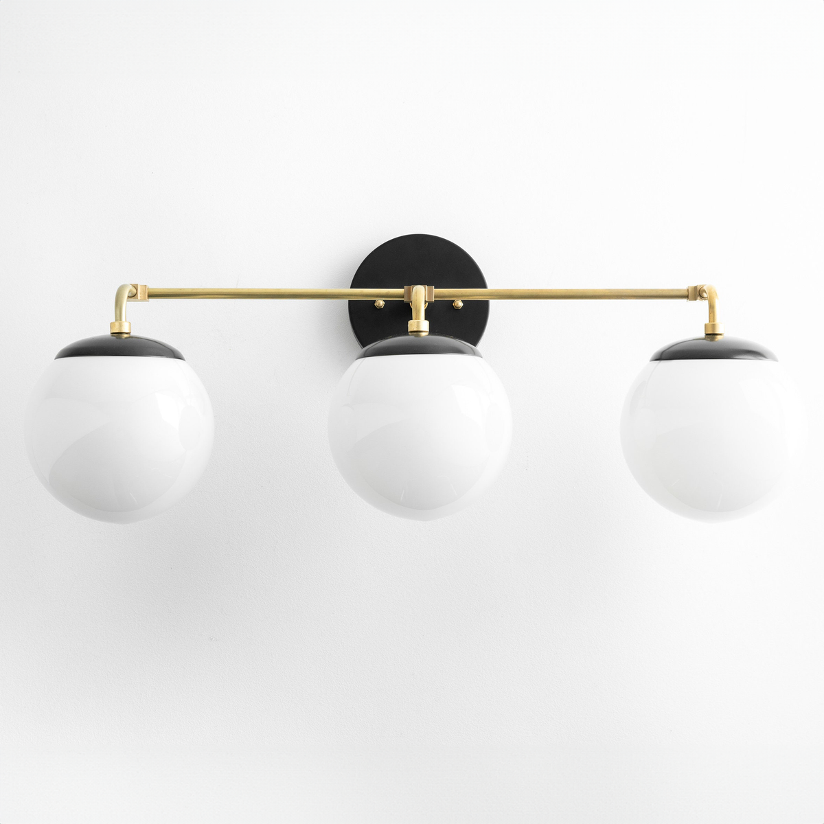 Mid-century modern vanity light with three white globe bulbs and a black circular wall mount with brass horizontal rod. - VANITY LIGHT MODEL NO. 9319