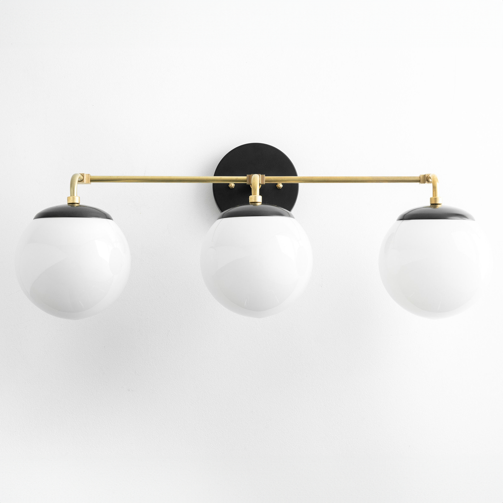 Mid-century modern vanity light with three white globe bulbs and a black circular wall mount with brass horizontal rod. - VANITY LIGHT MODEL NO. 9319