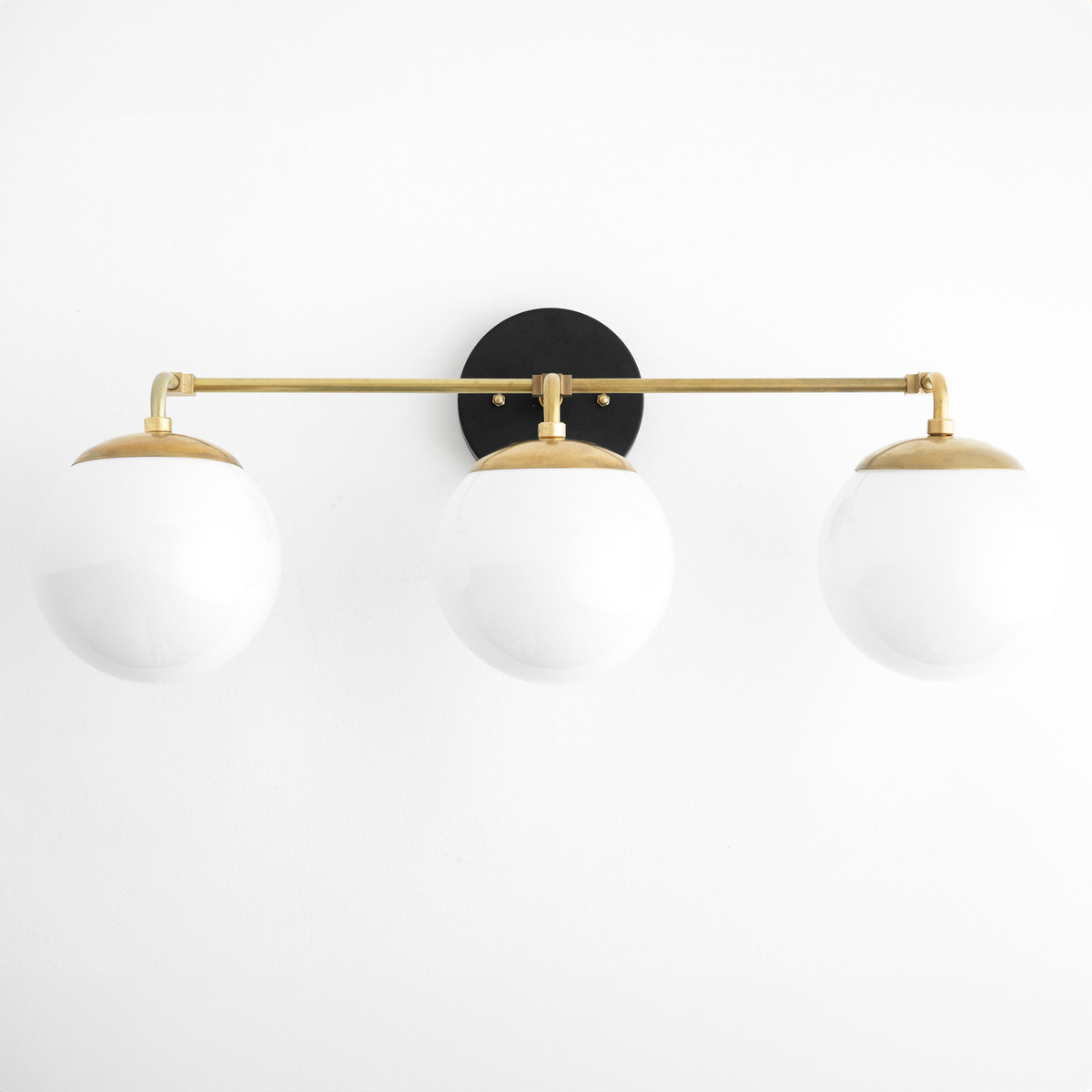 Mid-century modern vanity light with three white glass globes and a black and raw brass finish. - VANITY LIGHT MODEL NO. 9319