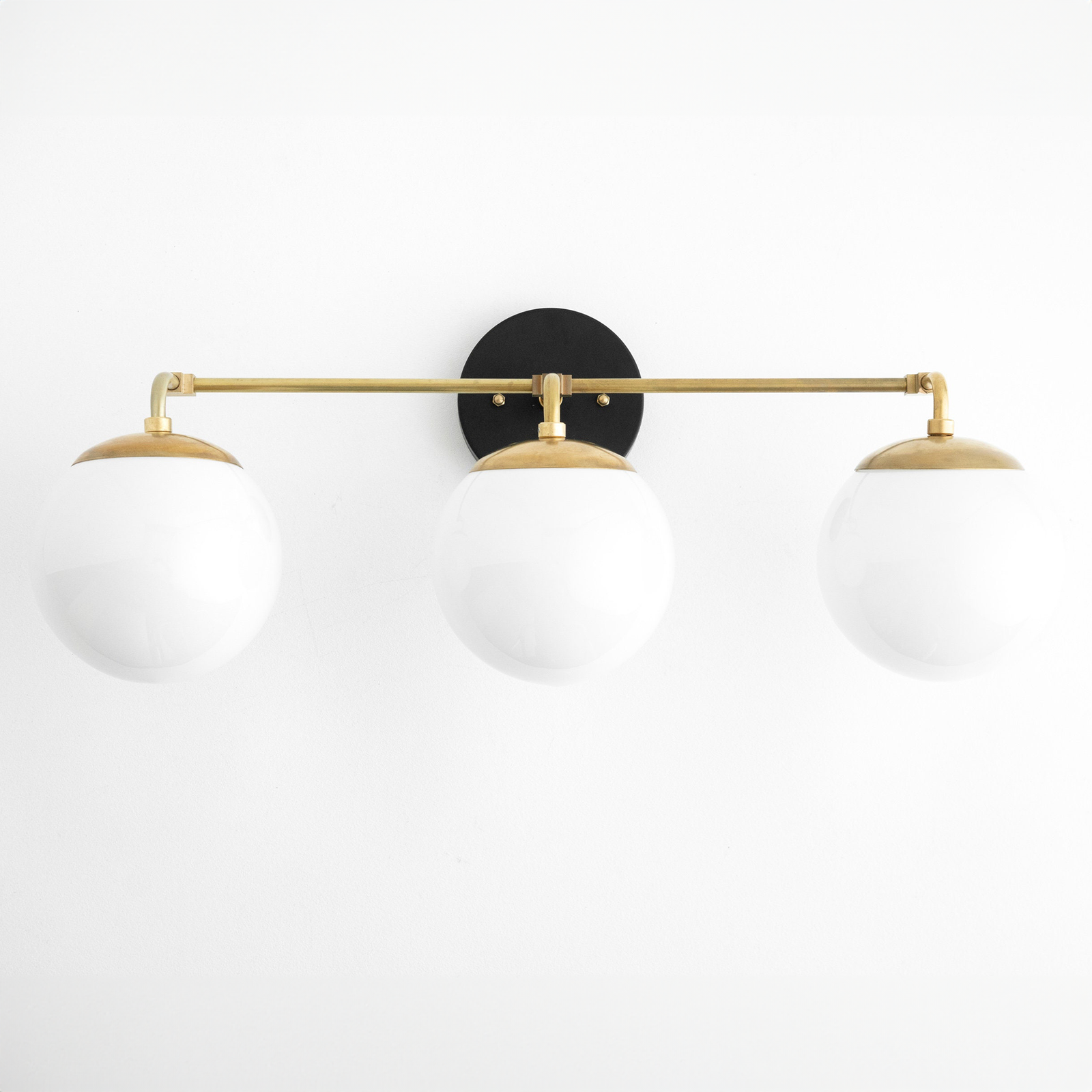 Mid-century modern vanity light with three white glass globes and a black and raw brass finish. - VANITY LIGHT MODEL NO. 9319