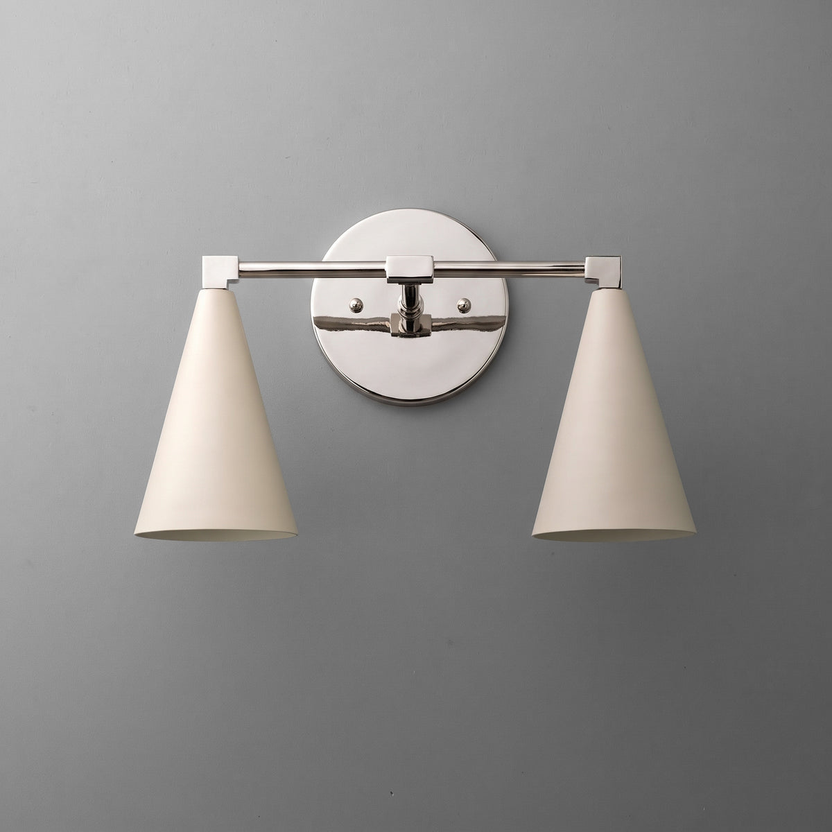 Two-light vanity light in Polished Nickel with Cream cone shades on a straight arm and a round wall plate. - VANITY LIGHT MODEL NO. 1184