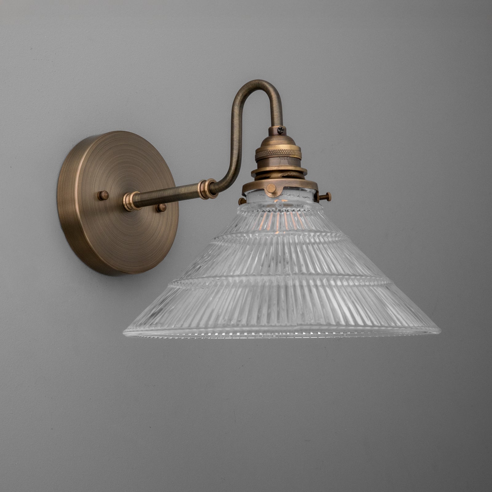 Wall-mounted sconce with antique brass finish and clear ribbed glass conical shade. - SCONCE MODEL NO. 4703