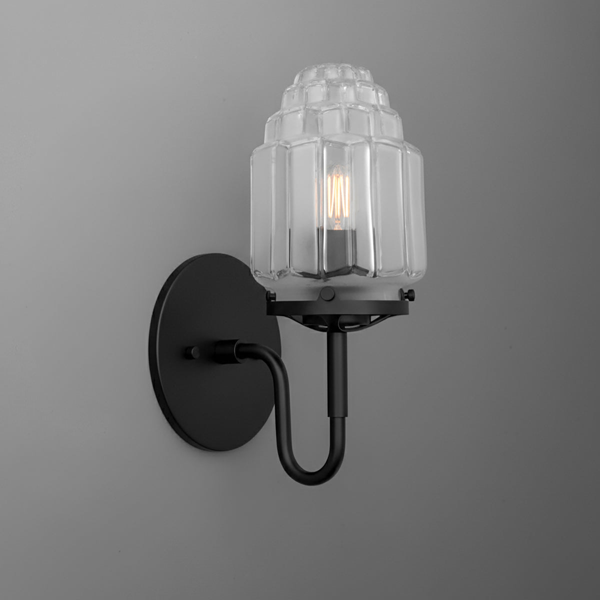 Black metal wall sconce with clear ribbed glass shade and exposed filament bulb. - SCONCE MODEL NO. 1035