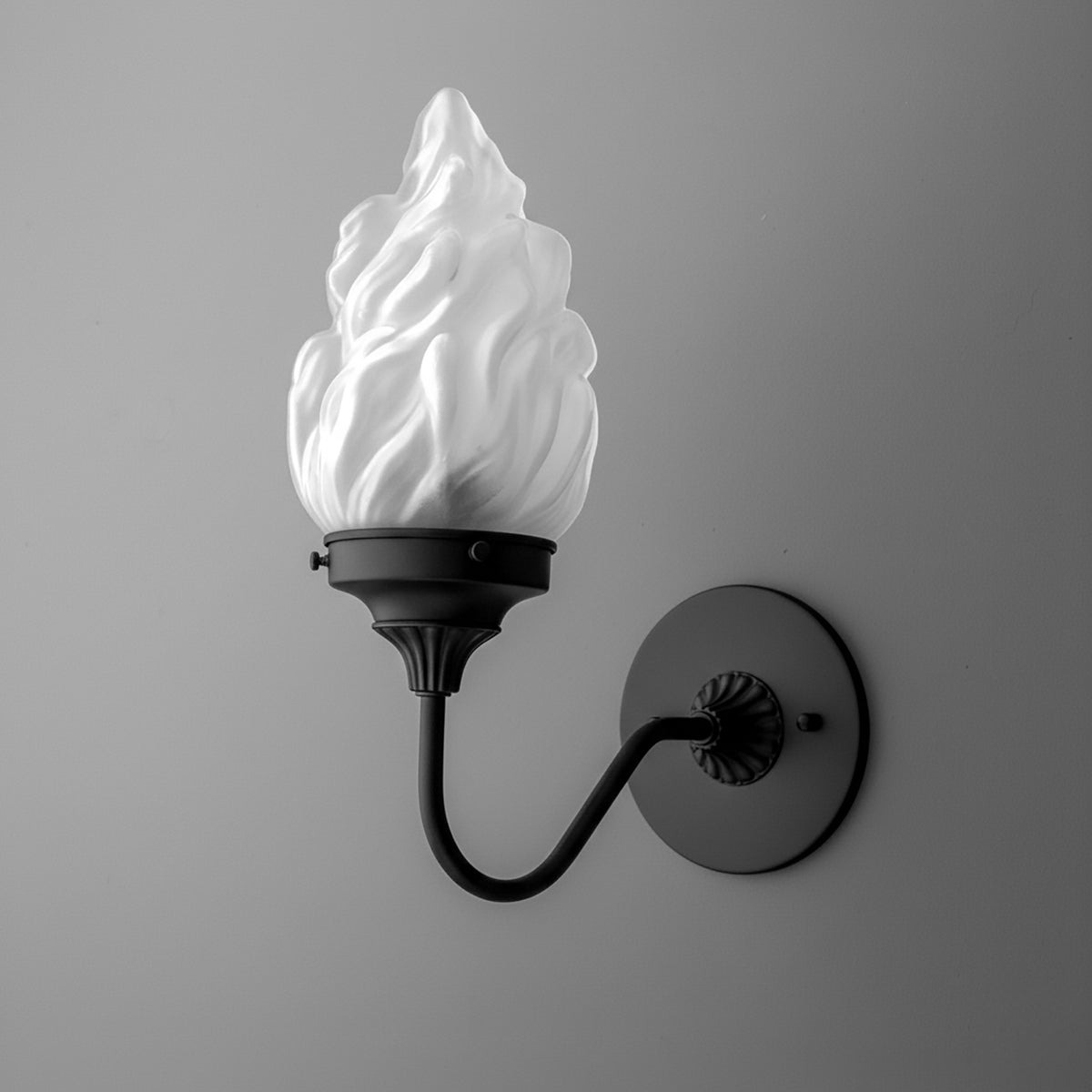 Black metal wall sconce with curved arm and white flame-shaped glass shade. - SCONCE MODEL NO. 1024