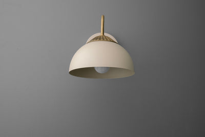 Raw brass wall sconce with cream dome-shaped shade and minimalist curved arm on gray background. - SCONCE MODEL NO. 9408
