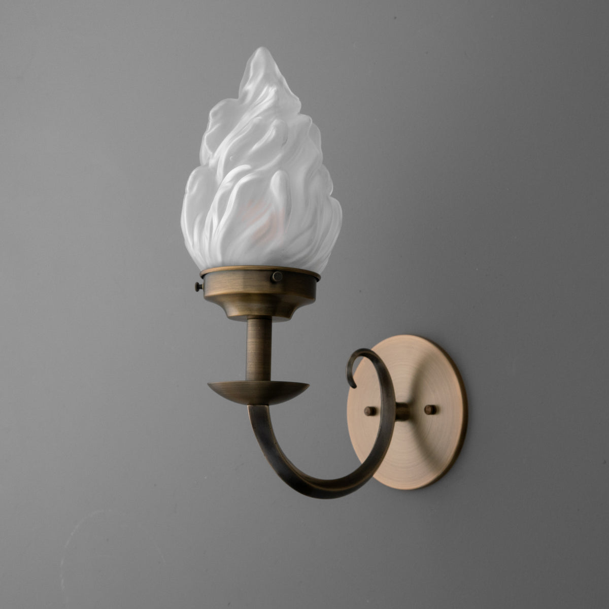 Antique brass 1-bulb wall sconce with frosted white flame-shaped glass shade. - SCONCE MODEL NO. 1057