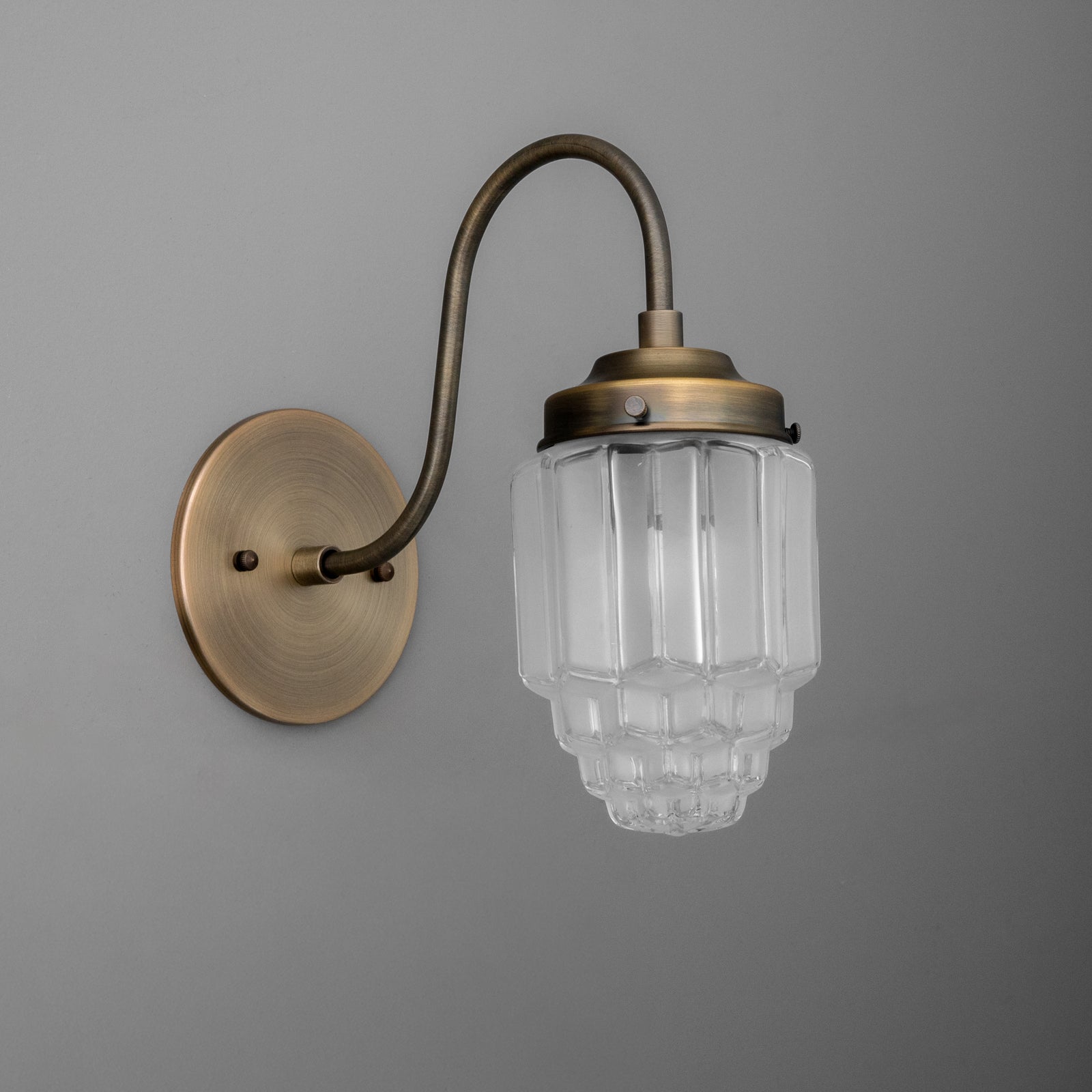 Antique brass wall sconce with curved arm and tiered frosted glass shade. - SCONCE MODEL NO. 1074
