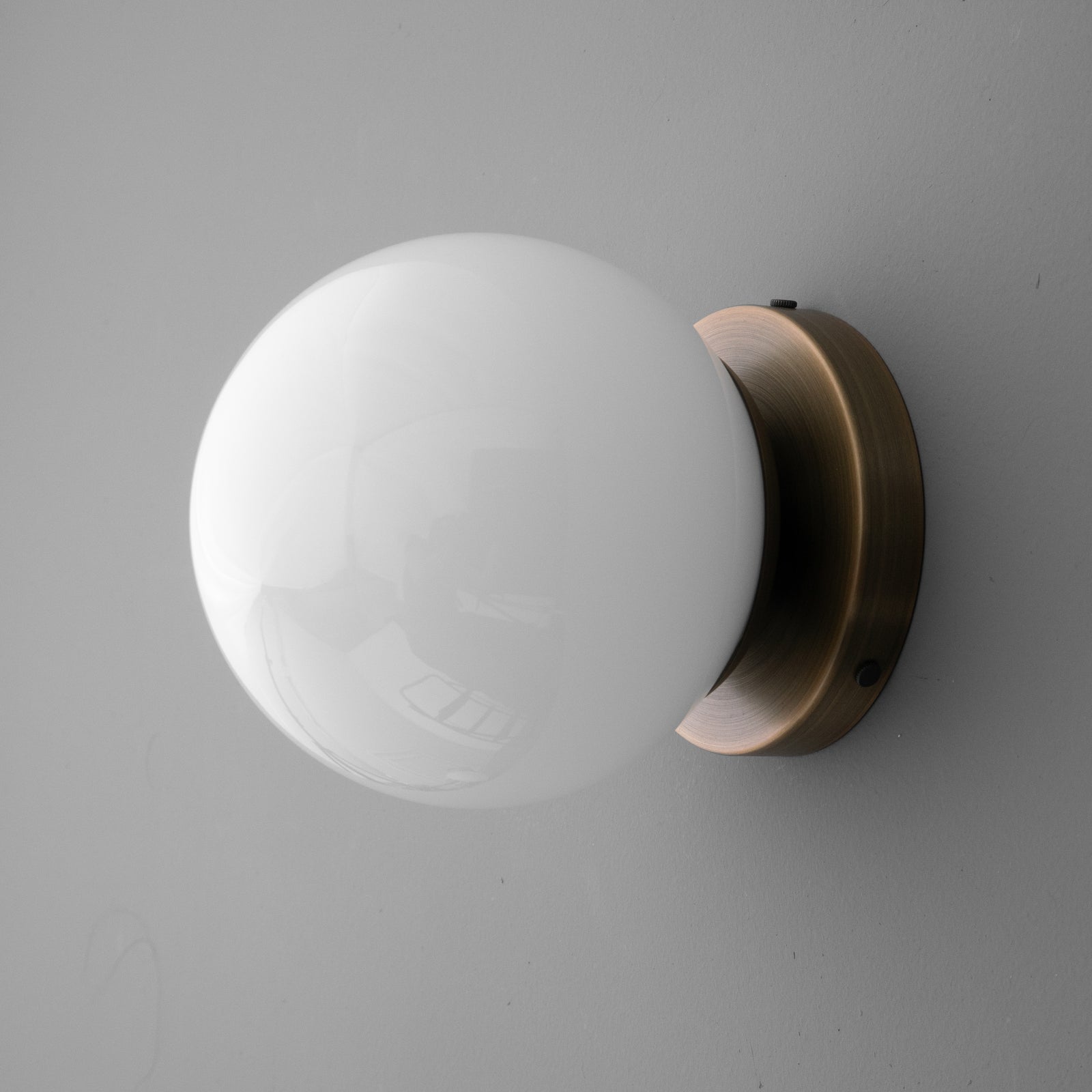 White glass globe sconce with a round antique brass wall mount and a smooth finish. - SCONCE MODEL NO. 3825
