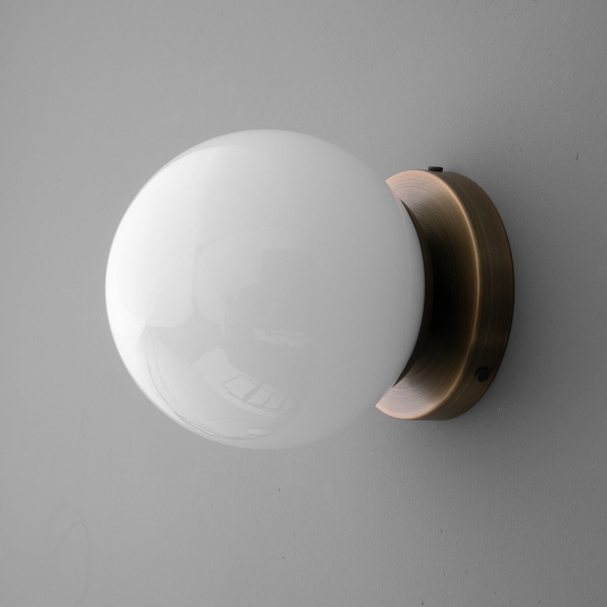 Round white glass globe sconce with antique brass circular wall mount. - SCONCE MODEL NO. 3825