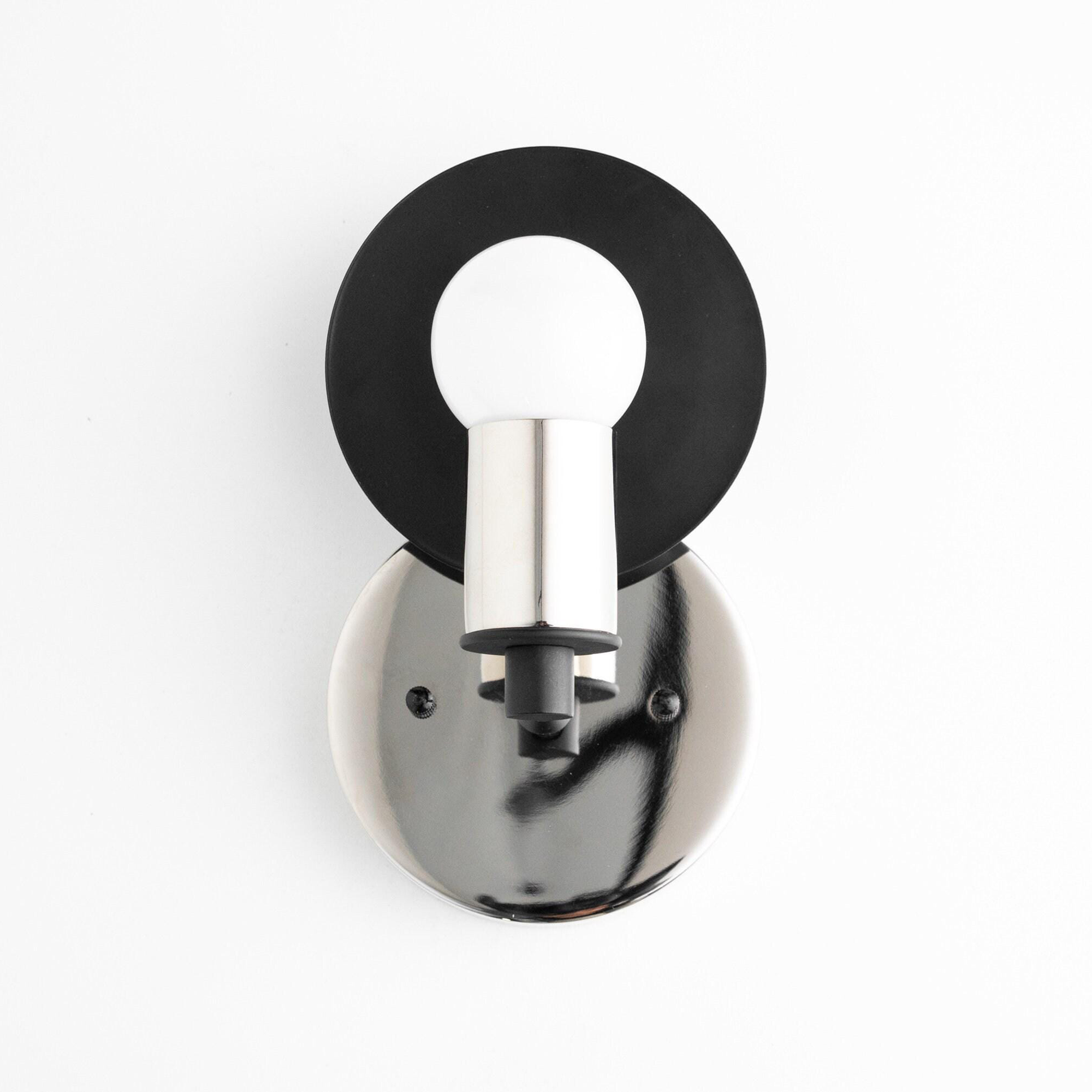 Art Deco sconce with a polished nickel round base, black circular backplate, and bare bulb holder. - SCONCE MODEL NO. 8677
