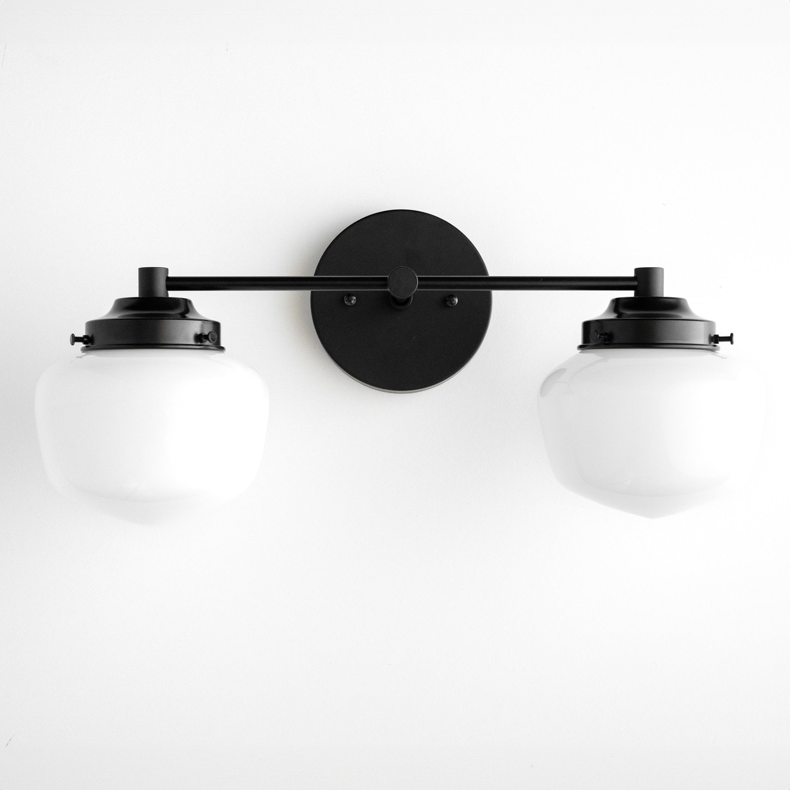 Mid-century modern black metal vanity light with two white globe shades and round wall plate. - VANITY LIGHT MODEL NO. 5799