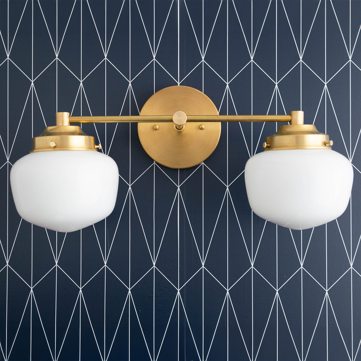 Mid-century modern double globe vanity light in sealed brass finish against navy geometric wallpaper. - VANITY LIGHT MODEL NO. 5799