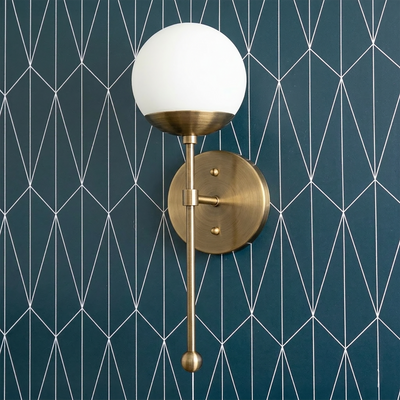 Art Deco style wall sconce with matte brass finish, white globe shade, and long vertical rod against geometric teal. - SCONCE MODEL NO. 1048