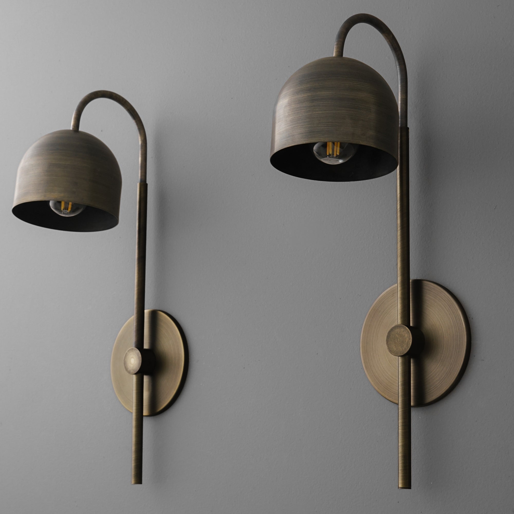Pair of antique brass wall sconces with curved arms and dome-shaped shades, exposed bulbs visible. - Sconce Model No. 7340