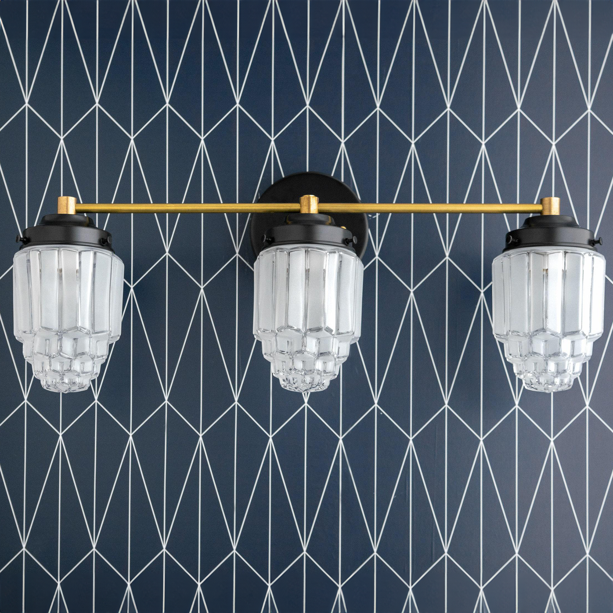 Three-bulb vanity light with tiered glass globes and a horizontal brass bar mounted on black fixtures. - VANITY LIGHT MODEL NO. 3918