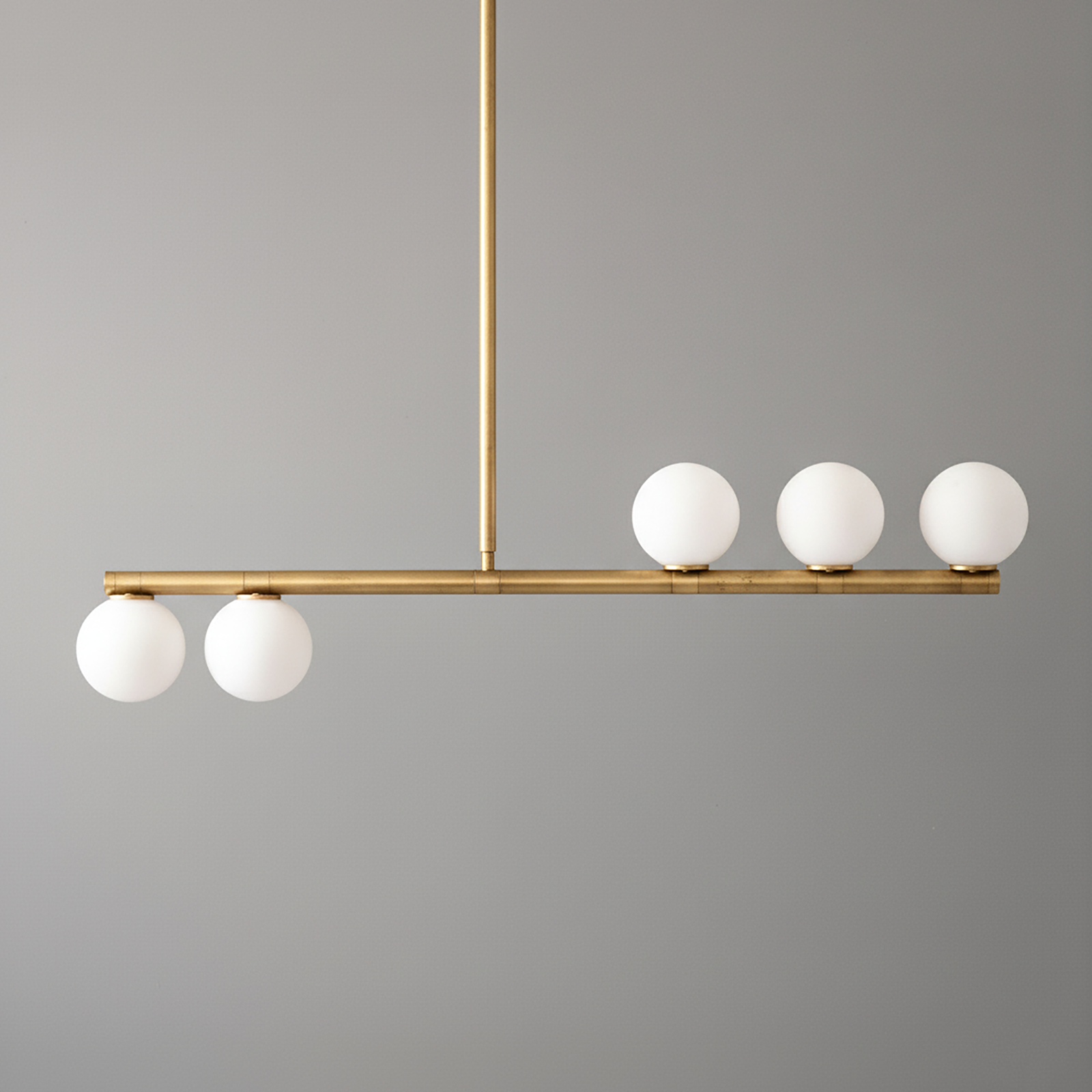 Linear brass chandelier with five white globe lights in a minimalist mid-century modern design. - CHANDELIER MODEL NO. 6507
