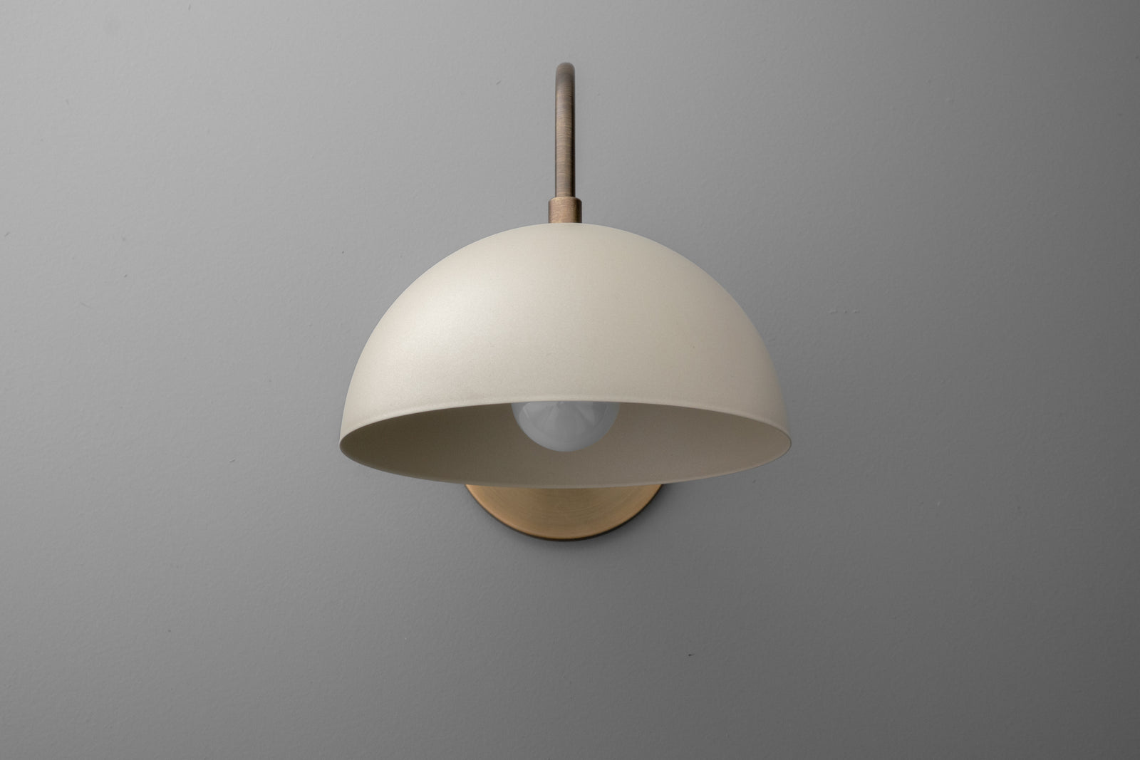 Antique brass dome wall sconce with cream shade and exposed bulb on gray background. - SCONCE MODEL NO. 9092