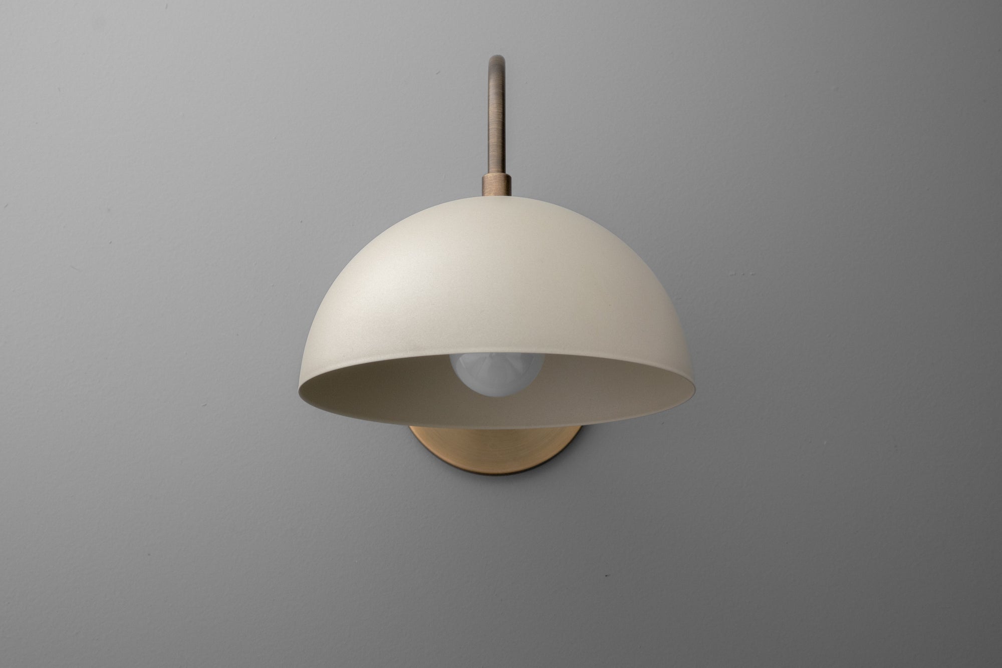 Antique brass dome wall sconce with cream shade and exposed bulb on gray background. - SCONCE MODEL NO. 9092