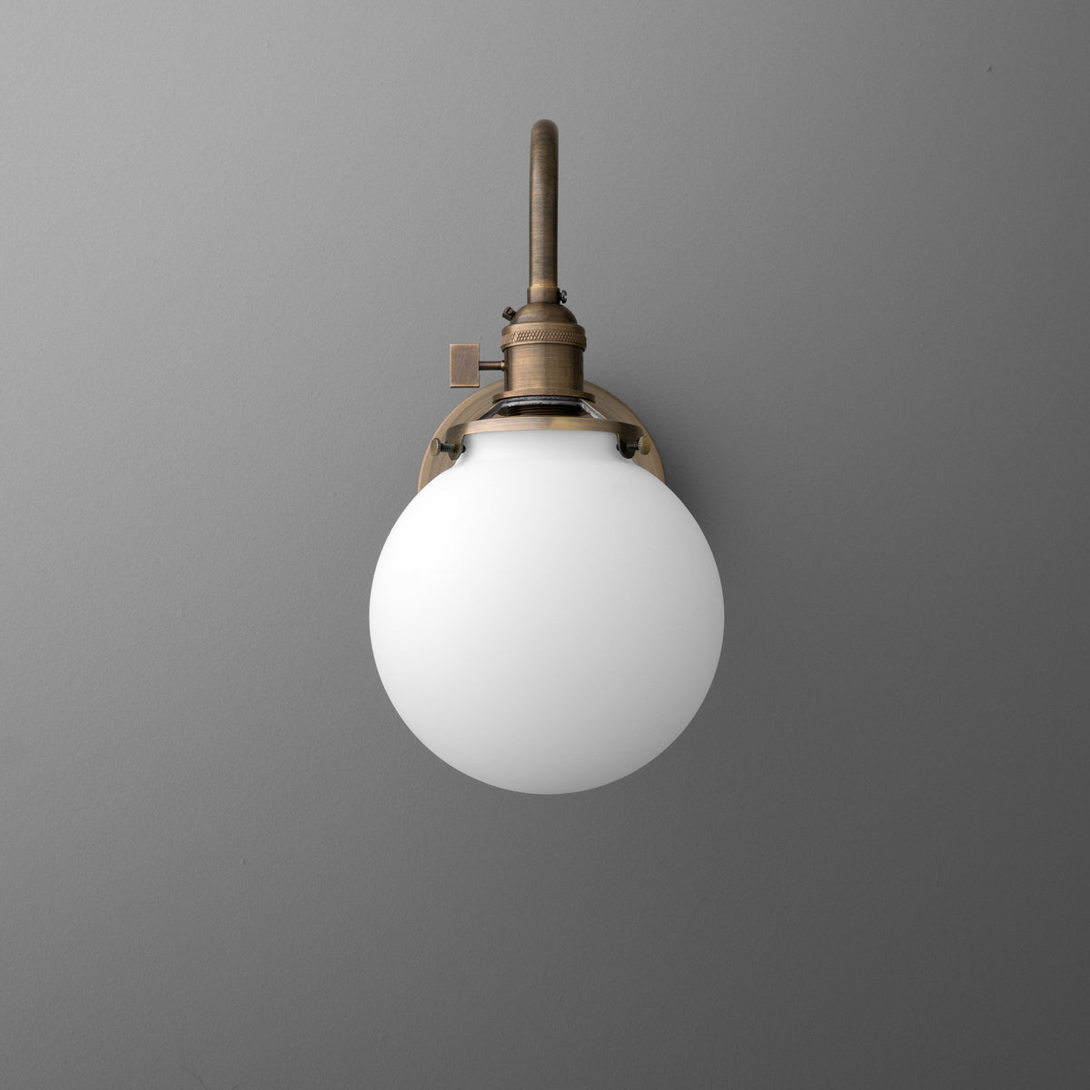 Bronze metal wall sconce with a white frosted glass globe shade and a slim vertical arm. - SCONCE MODEL NO. 0017
