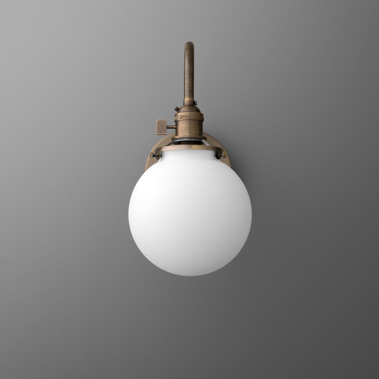 Bronze metal wall sconce with a white frosted glass globe shade and a slim vertical arm. - SCONCE MODEL NO. 0017