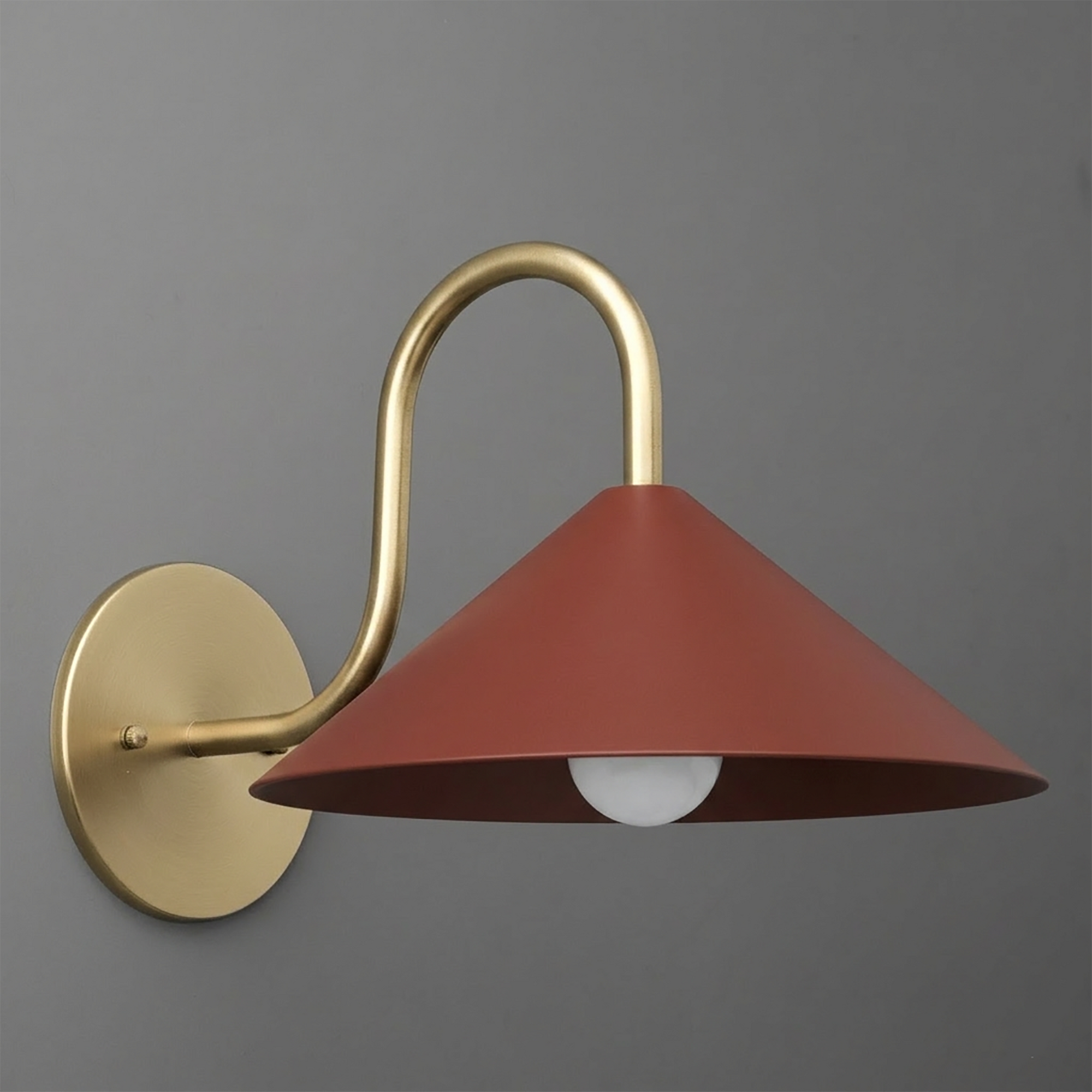 Wall-mounted sconce with a matte gold curved arm and round base, featuring a wide conical rust-colored metal shade. - SCONCE MODEL NO. 1015