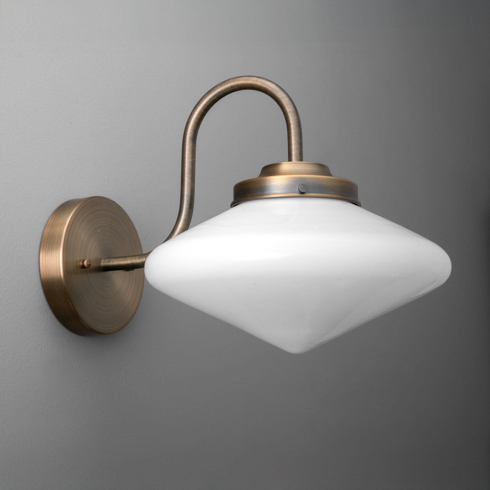Wall sconce with curved antique brass arm and frosted white glass shade in a rounded diamond shape. - SCONCE MODEL NO. 1021