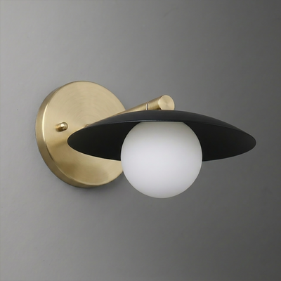 Wall sconce with matte black flat disc shade and frosted white globe bulb on brushed brass mount. - SCONCE MODEL NO. 9872