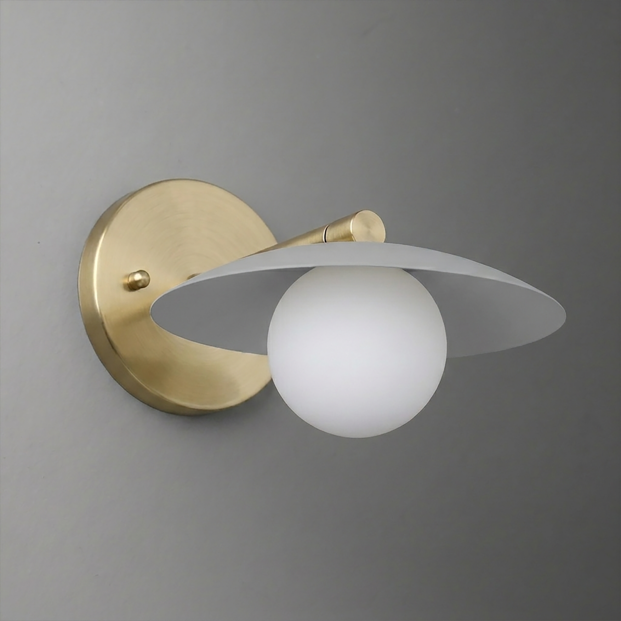 Wall sconce with brushed brass mount and white globe bulb under a flat, wide light gray metal shade. - SCONCE MODEL NO. 9872