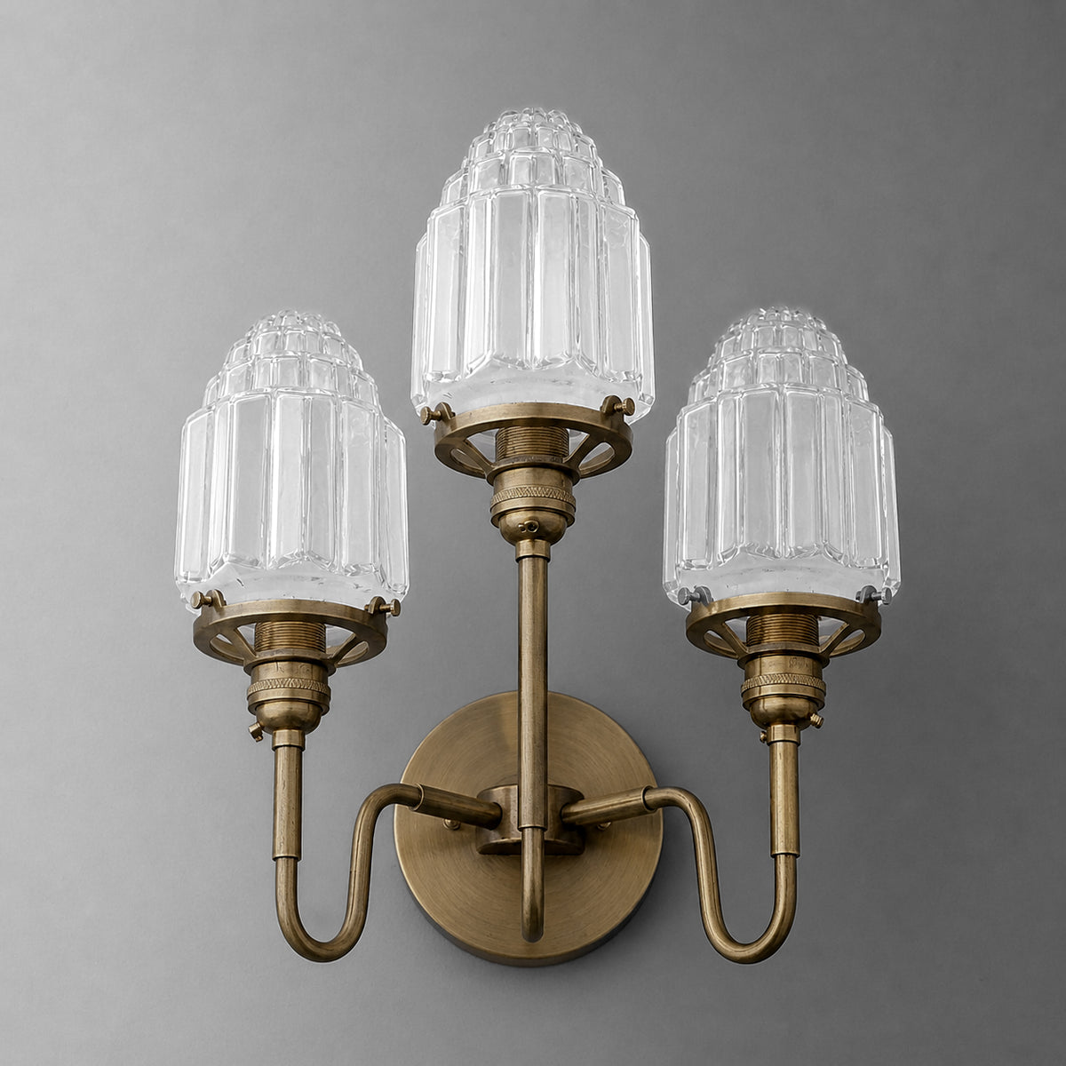 Three-bulb wall sconce with antique brass finish and clear ribbed glass shades, elegant vintage design. - SCONCE MODEL NO. 0070