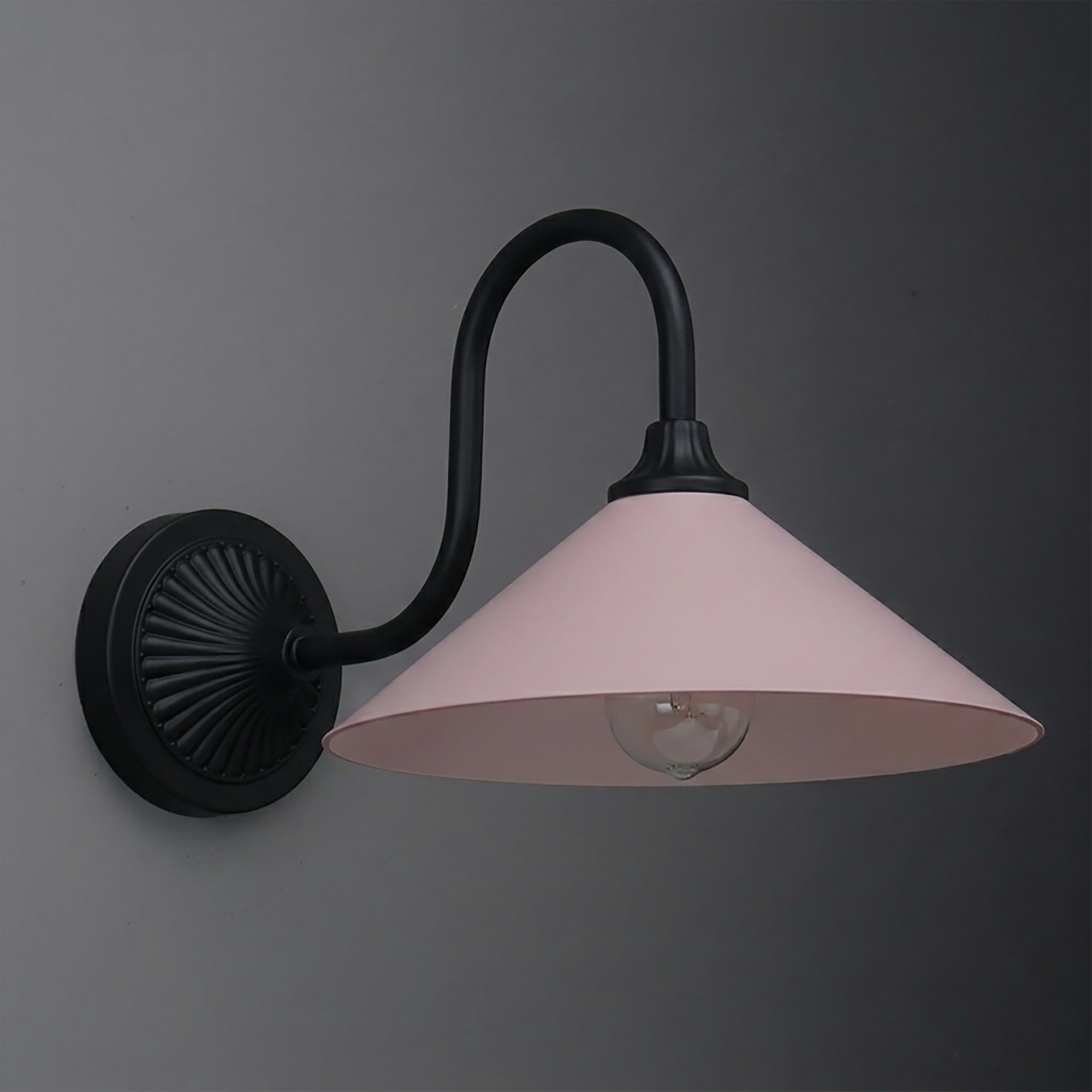 Wall sconce with matte black curved arm and round base, featuring a wide conical pale pink metal shade and exposed bulb. - SCONCE MODEL NO. 1031