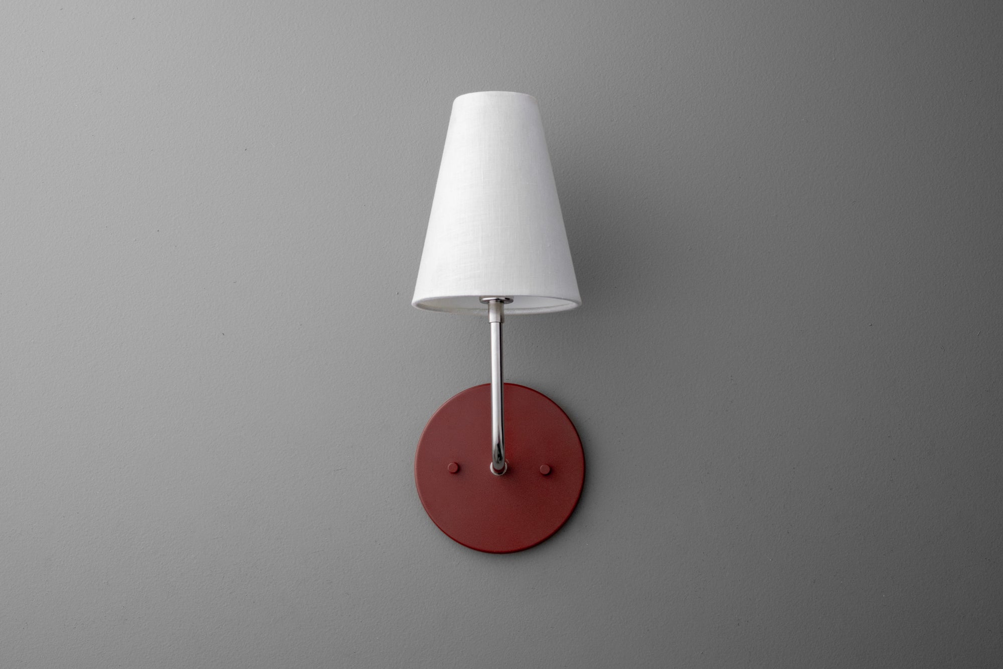 Wall sconce with polished nickel arm, white tapered fabric shade, and brick red round metal base. - SCONCE MODEL NO. 3928