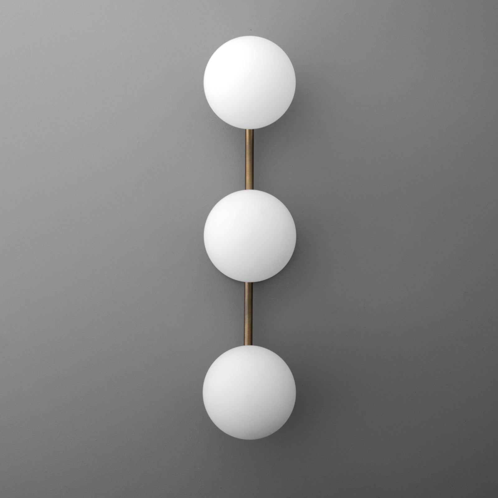 Modern wall sconce with three white frosted glass globes on a vertical brass rod. - SCONCE MODEL NO. 9250