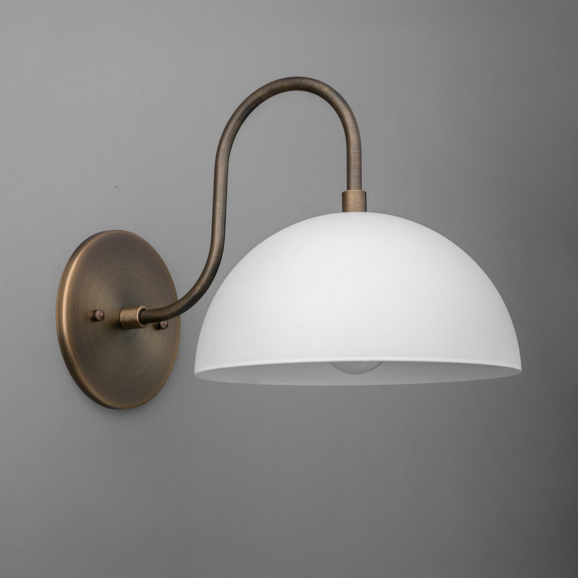 Wall-mounted sconce with a matte white dome shade and curved raw brass arm on a round brass base. - SCONCE MODEL NO. 9092