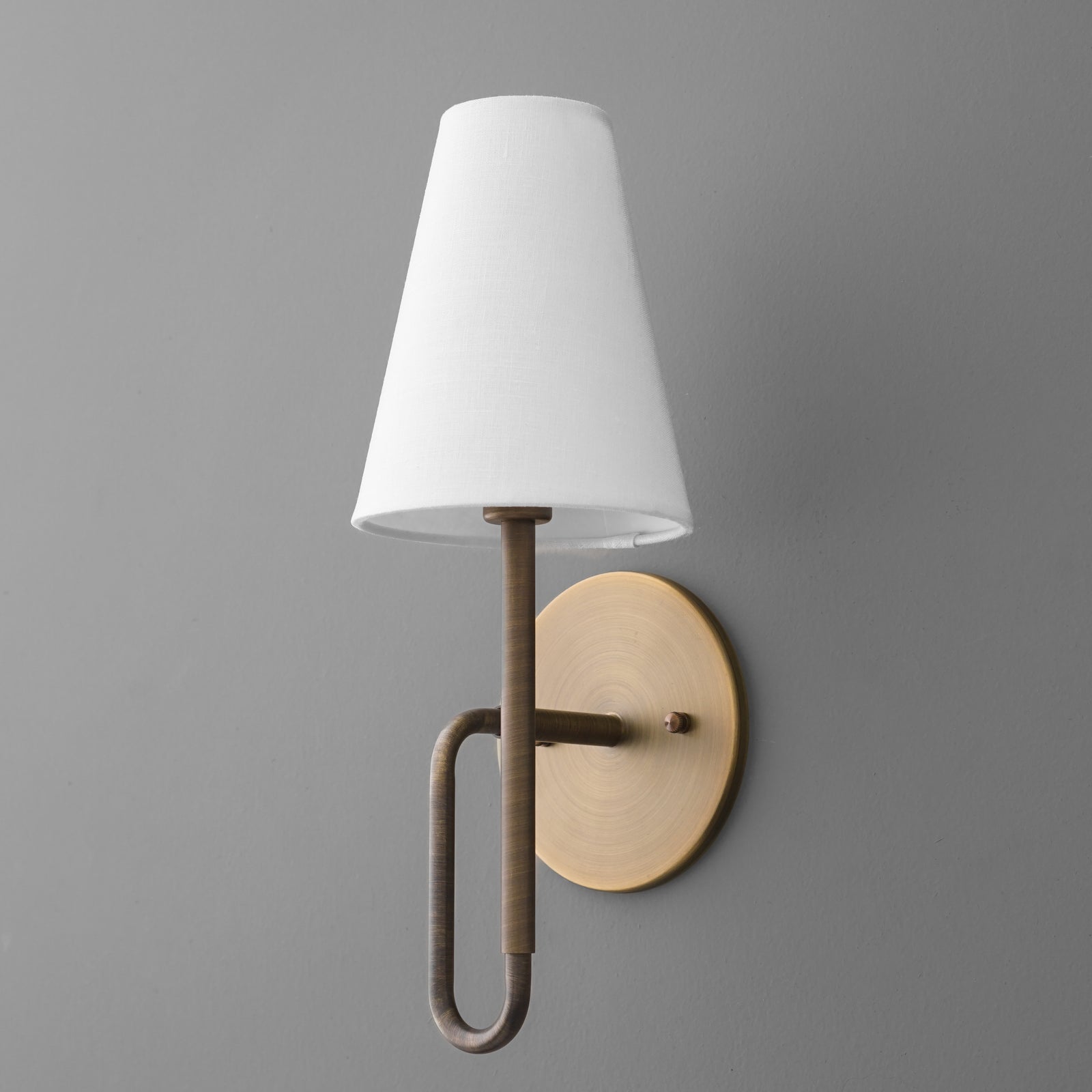 Wall sconce with matte gold oval backplate, curved gold arm, and white tapered fabric shade. - SCONCE MODEL NO. 1008