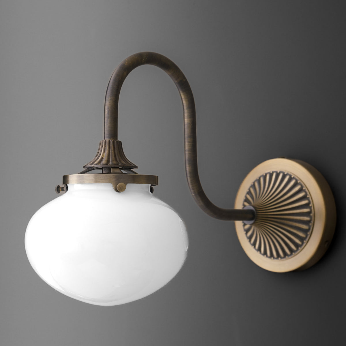 Sconce in Antique Brass with a gooseneck arm from a fluted fan wall plate holding a round opal glass bubble shade. - SCONCE MODEL NO. 5310