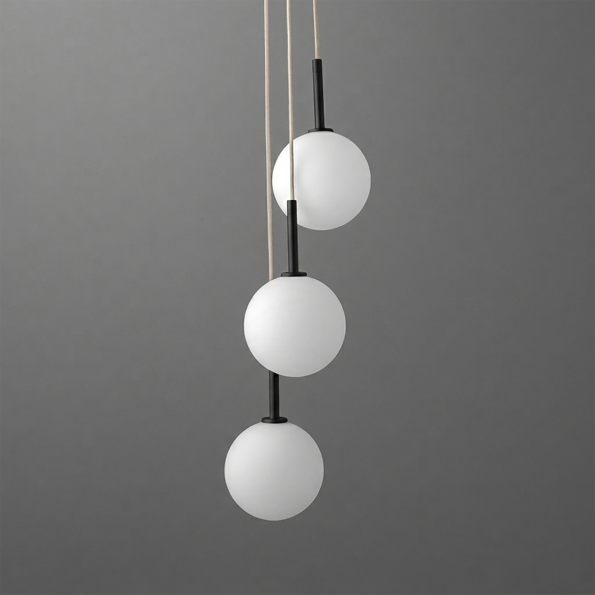 Three-globe chandelier with frosted white glass globes and black metal accents hanging vertically against dark gray. - CHANDELIER MODEL NO. 4701