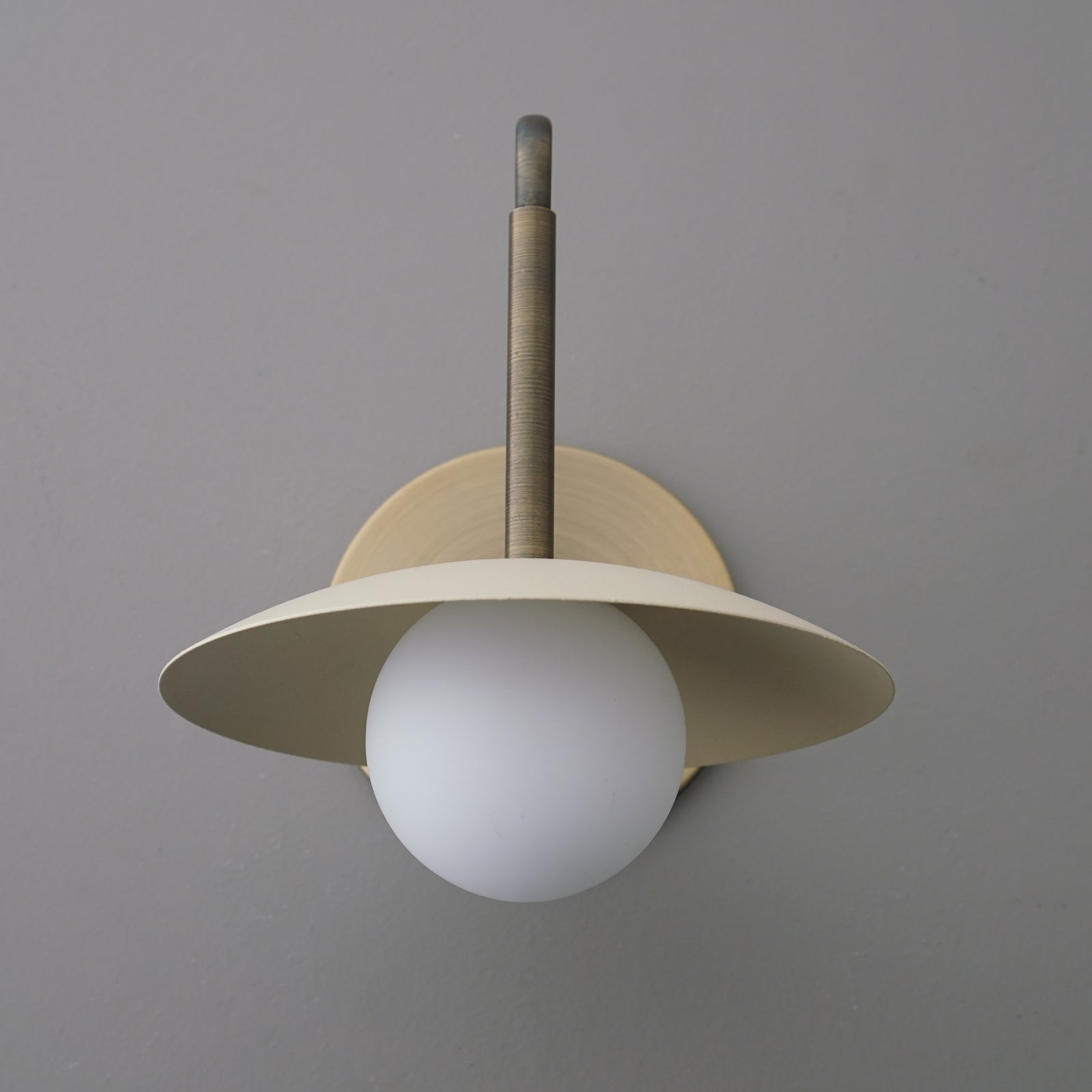 Matte gold metal wall sconce with a flat circular shade and white frosted glass globe bulb. - SCONCE MODEL NO. 1017