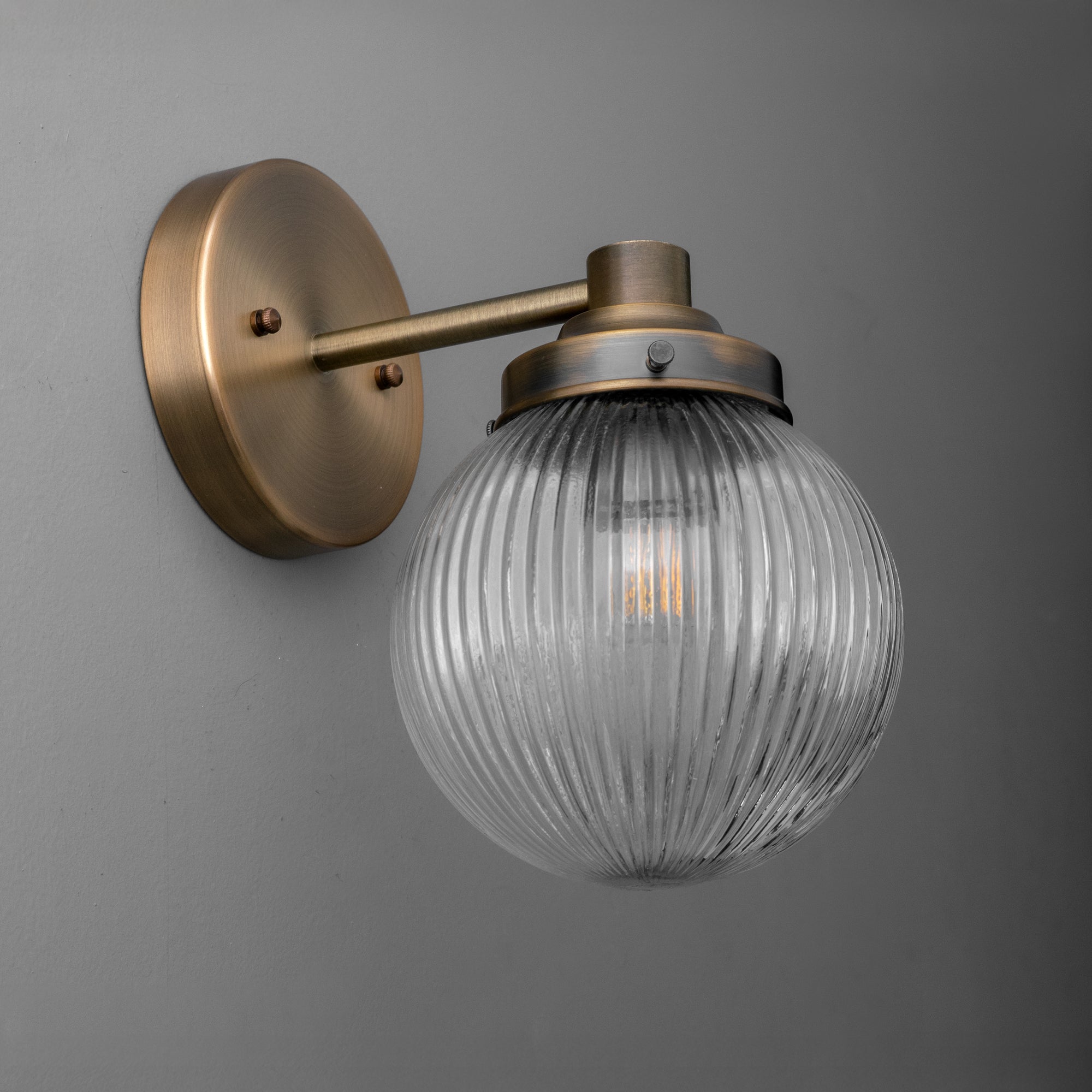 Antique brass wall sconce with ribbed clear glass globe shade and exposed filament bulb. - SCONCE MODEL NO. 7273