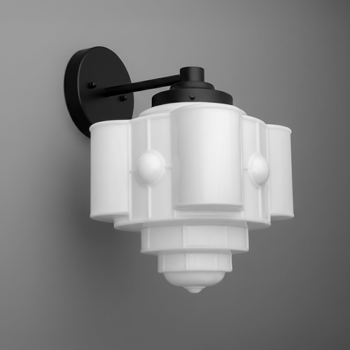 Black metal wall sconce with a tiered, geometric white glass shade and one bulb. - SCONCE MODEL NO. 1064