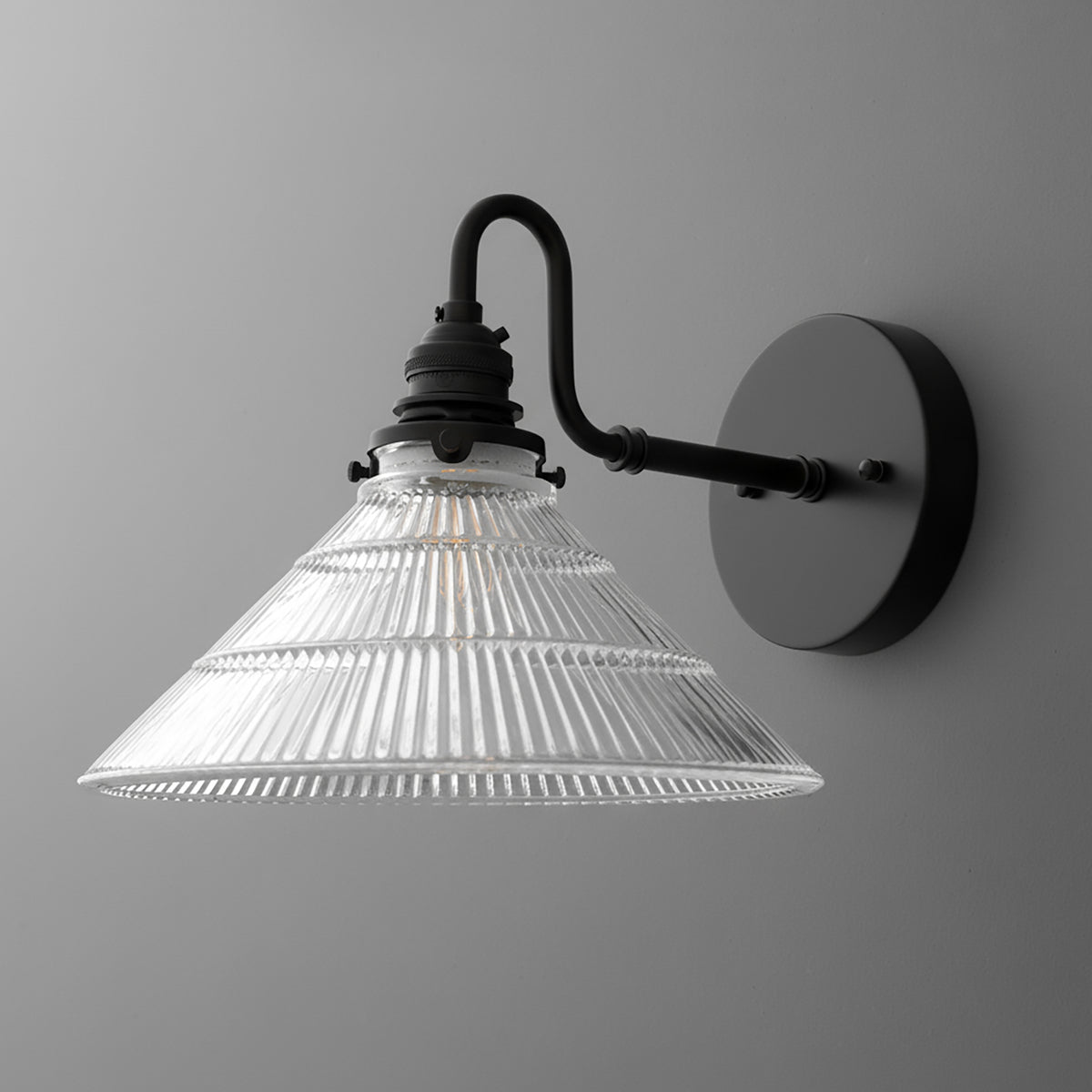 Matte black metal wall sconce with a clear ribbed glass conical shade and curved arm design. - SCONCE MODEL NO. 4703
