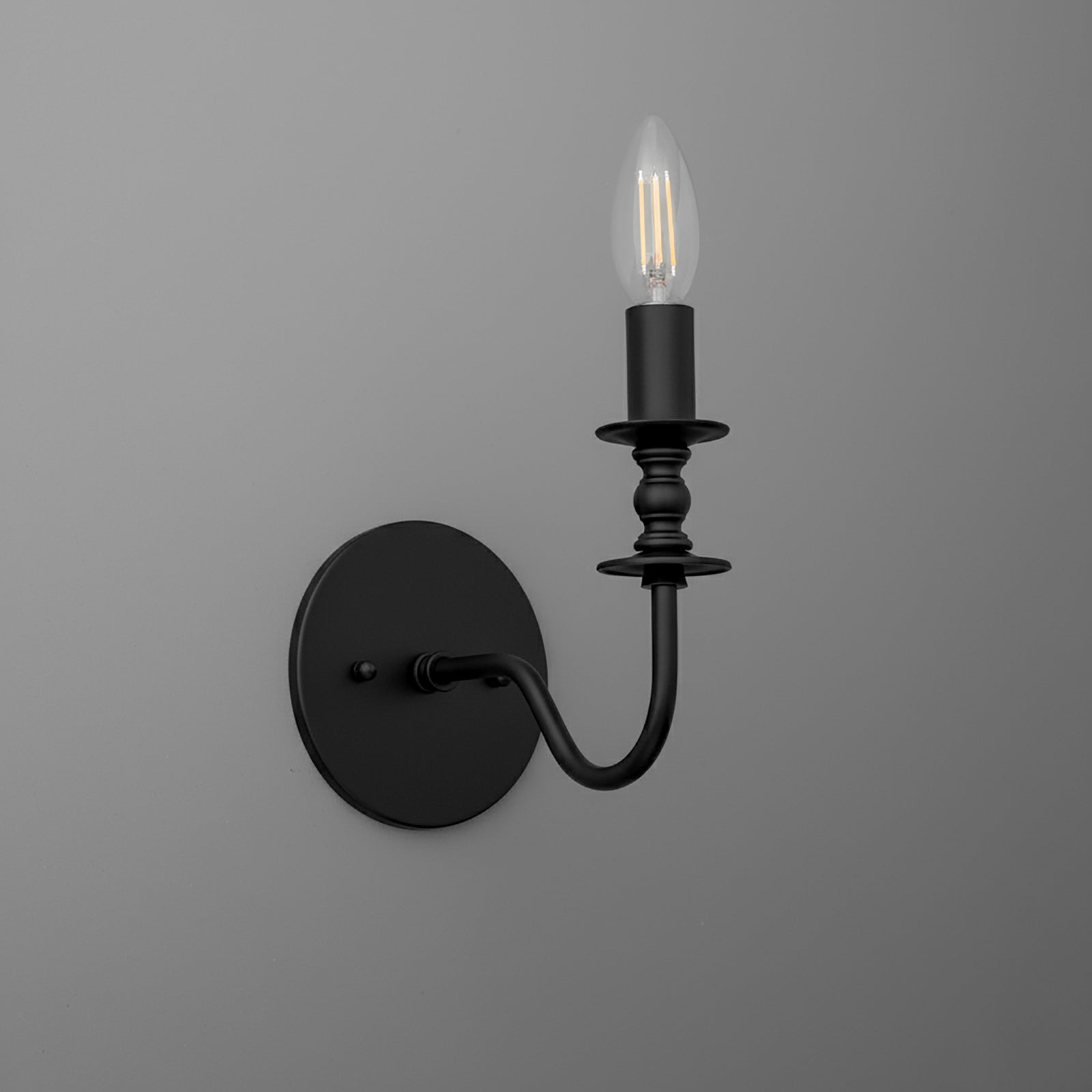 Matte black metal wall sconce with curved arm and candle-style bulb holder. - SCONCE MODEL NO. 9915