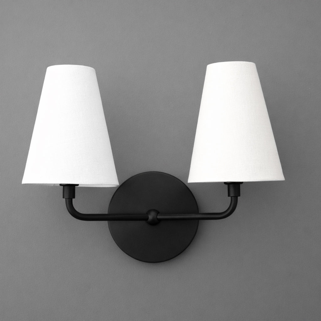 Double-bulb wall sconce with matte black metal base and two white tapered fabric shades. - SCONCE MODEL NO. 0823