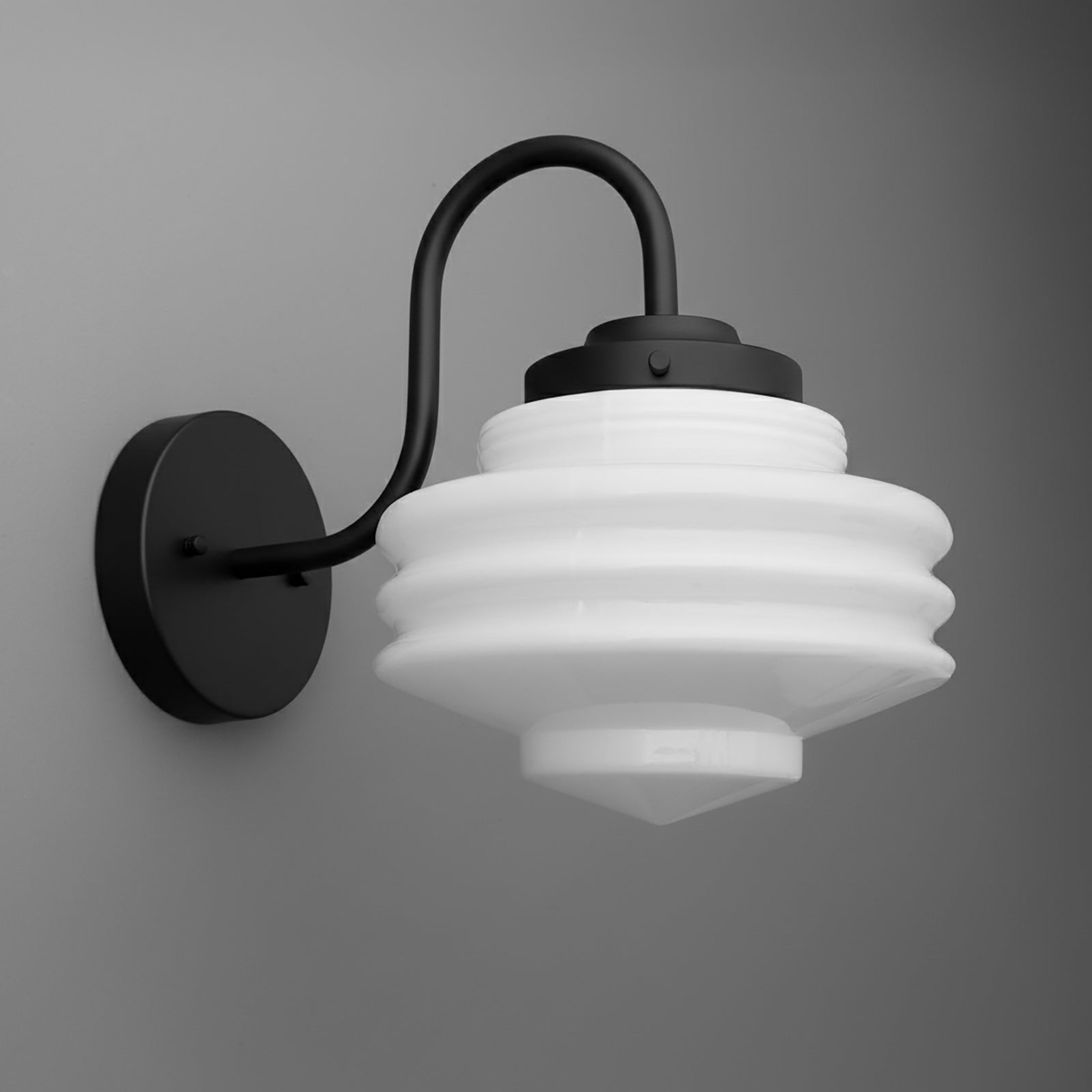 Black metal wall sconce with curved arm and ribbed white glass shade in a tiered, stepped design. - SCONCE MODEL NO. 1096