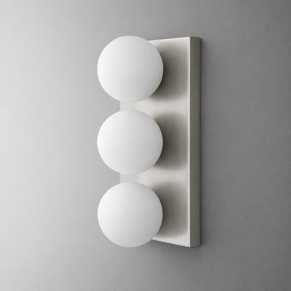 Modern wall sconce with three matte white glass globe bulbs mounted vertically on a brushed metal rectangular base. - SCONCE MODEL NO. 2623