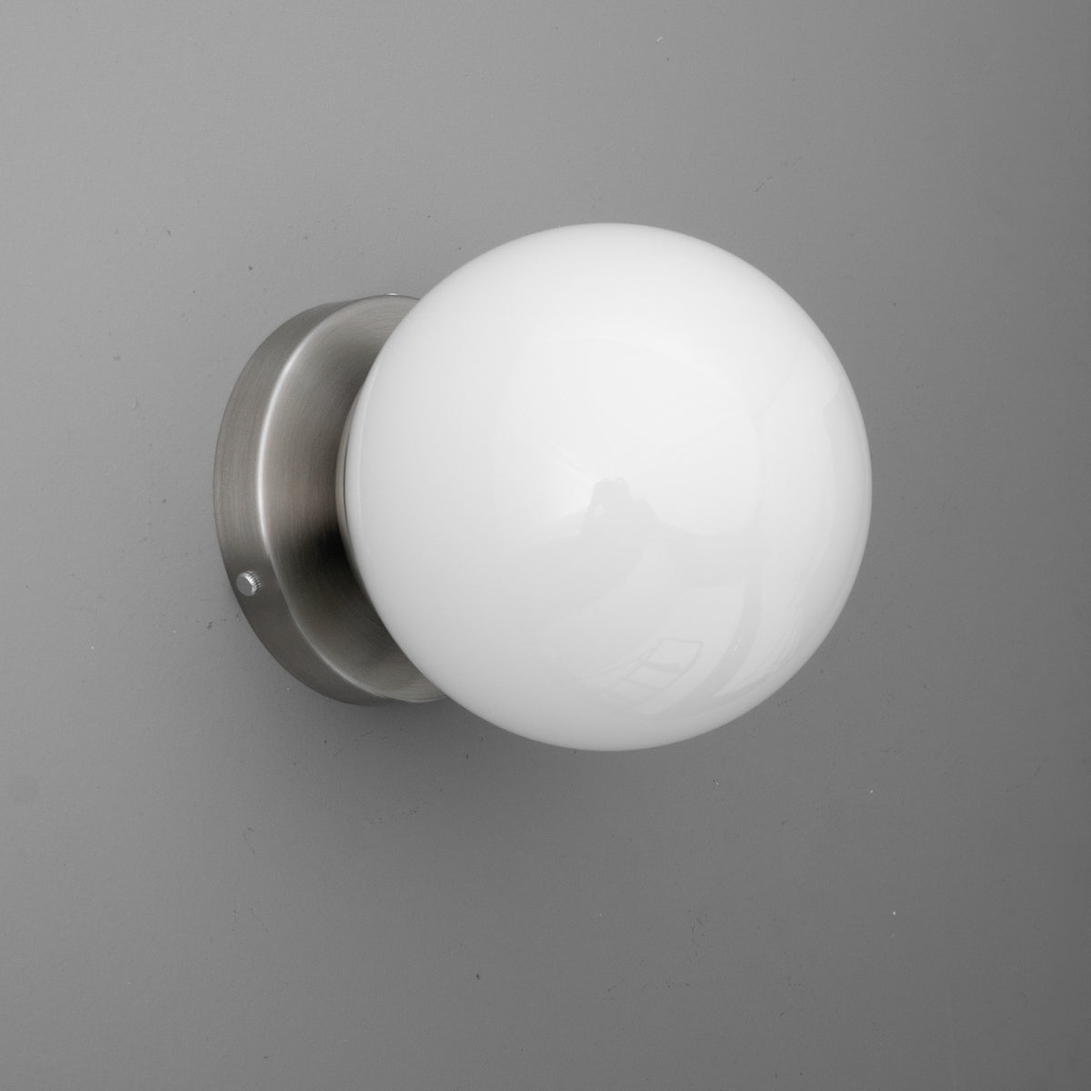 Wall-mounted sconce with a round white glass globe and brushed metal base. - SCONCE MODEL NO. 3825