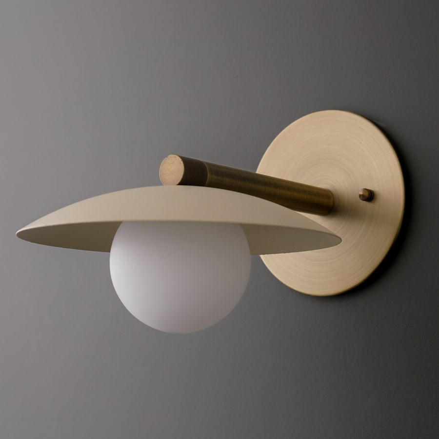 Antique brass sconce with cream flat metal shade and frosted globe bulb on round wall plate. - SCONCE MODEL NO. 9875