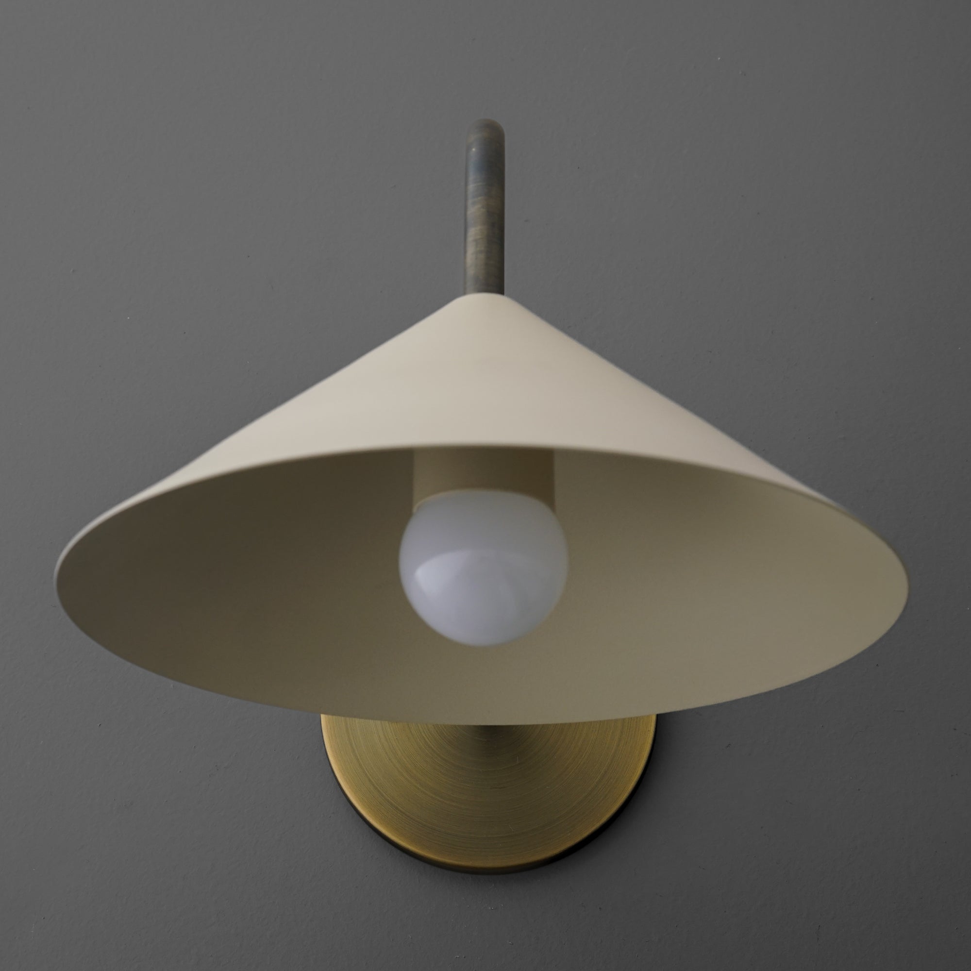 Cone-shaped cream metal sconce with exposed white bulb and brass circular wall mount. - SCONCE MODEL NO. 1015