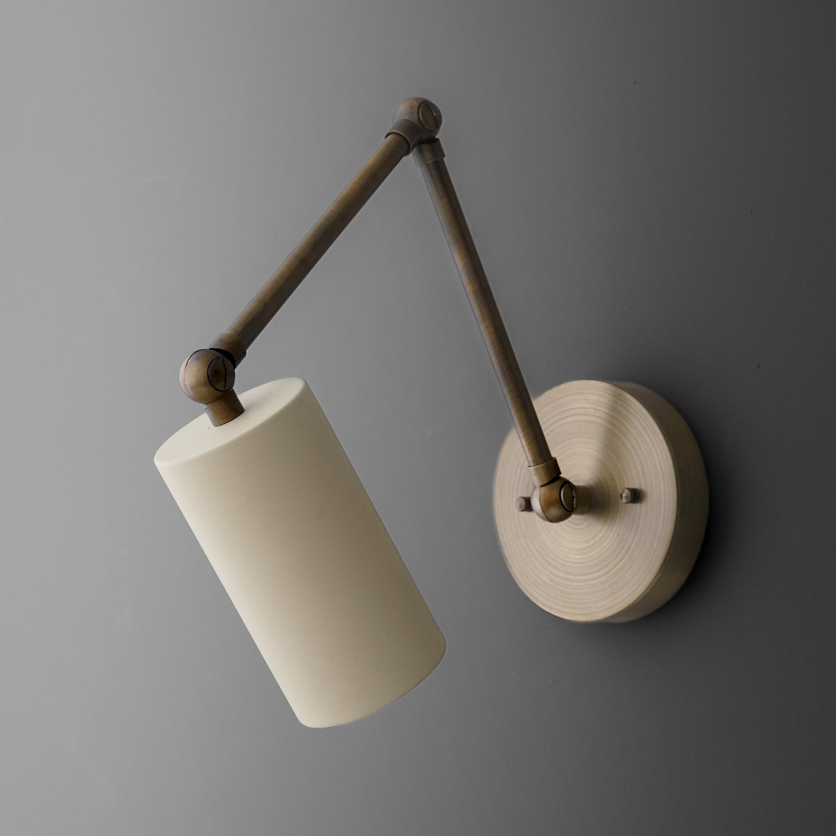 Wall-mounted sconce with adjustable dark metal arm and cylindrical white fabric shade. - SCONCE MODEL NO. 0357