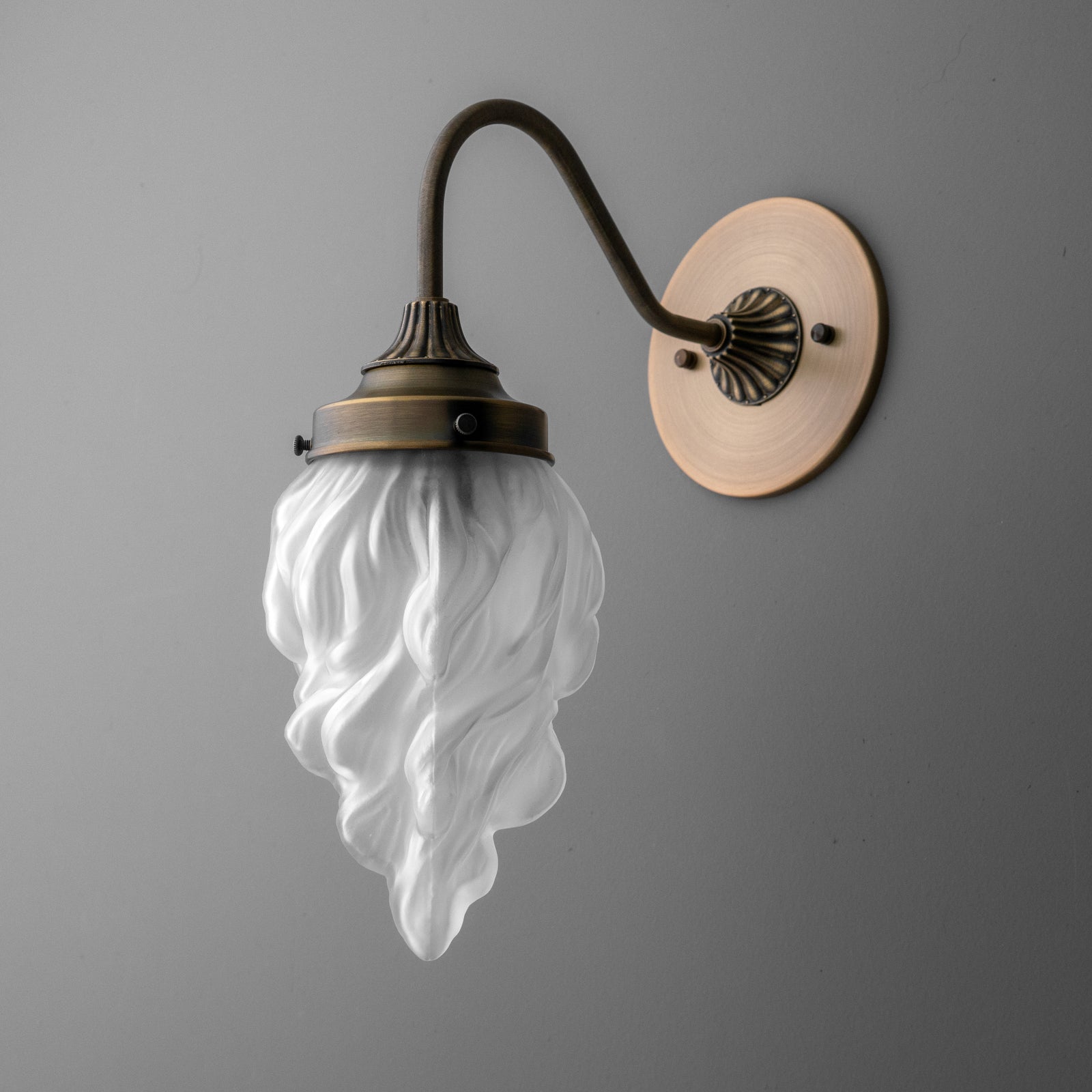 Antique bronze wall sconce with fluted round base and frosted glass shade shaped like flowing flames. - SCONCE MODEL NO. 1024