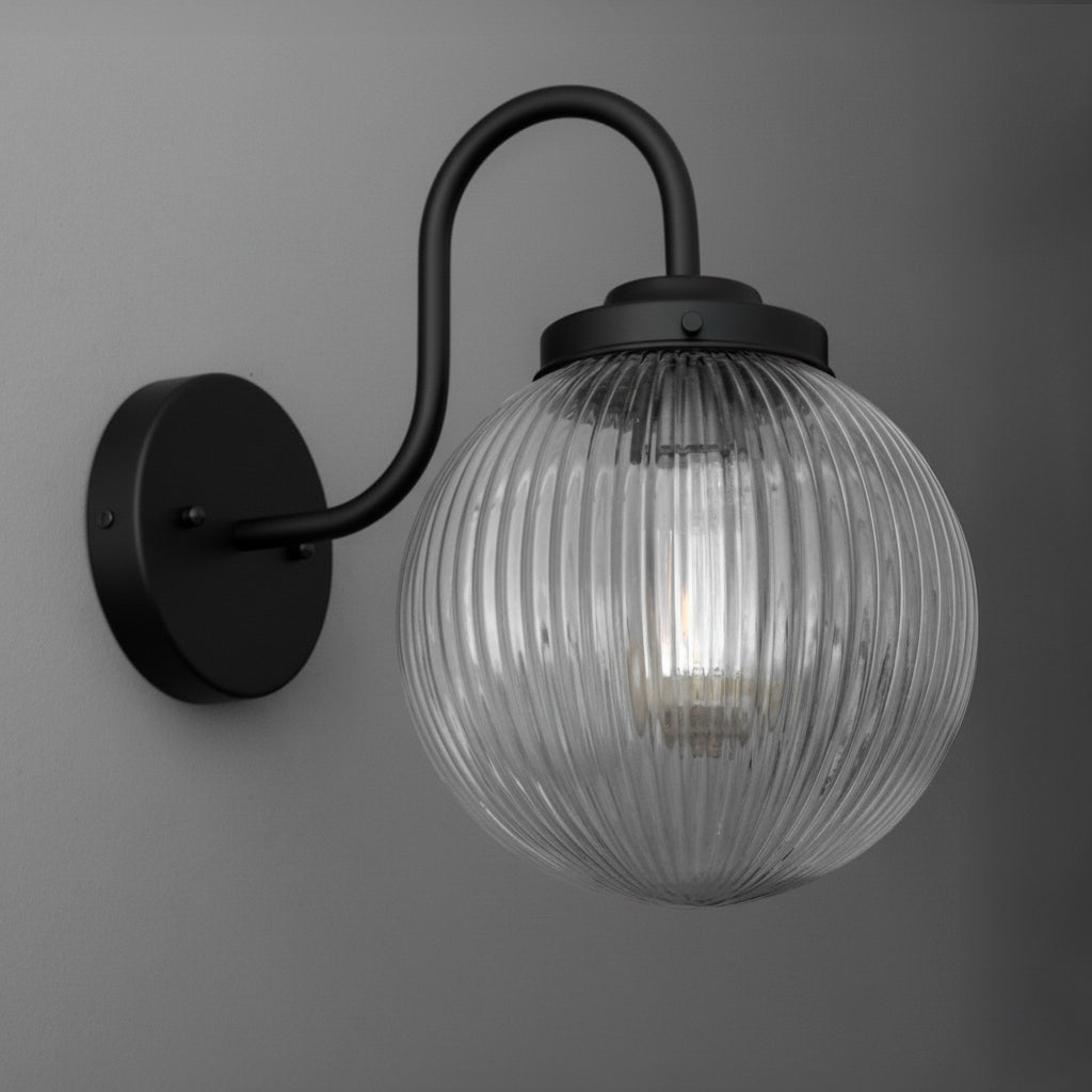 Black metal wall sconce with curved arm and ribbed clear glass globe shade containing one bulb. - SCONCE MODEL NO. 1009